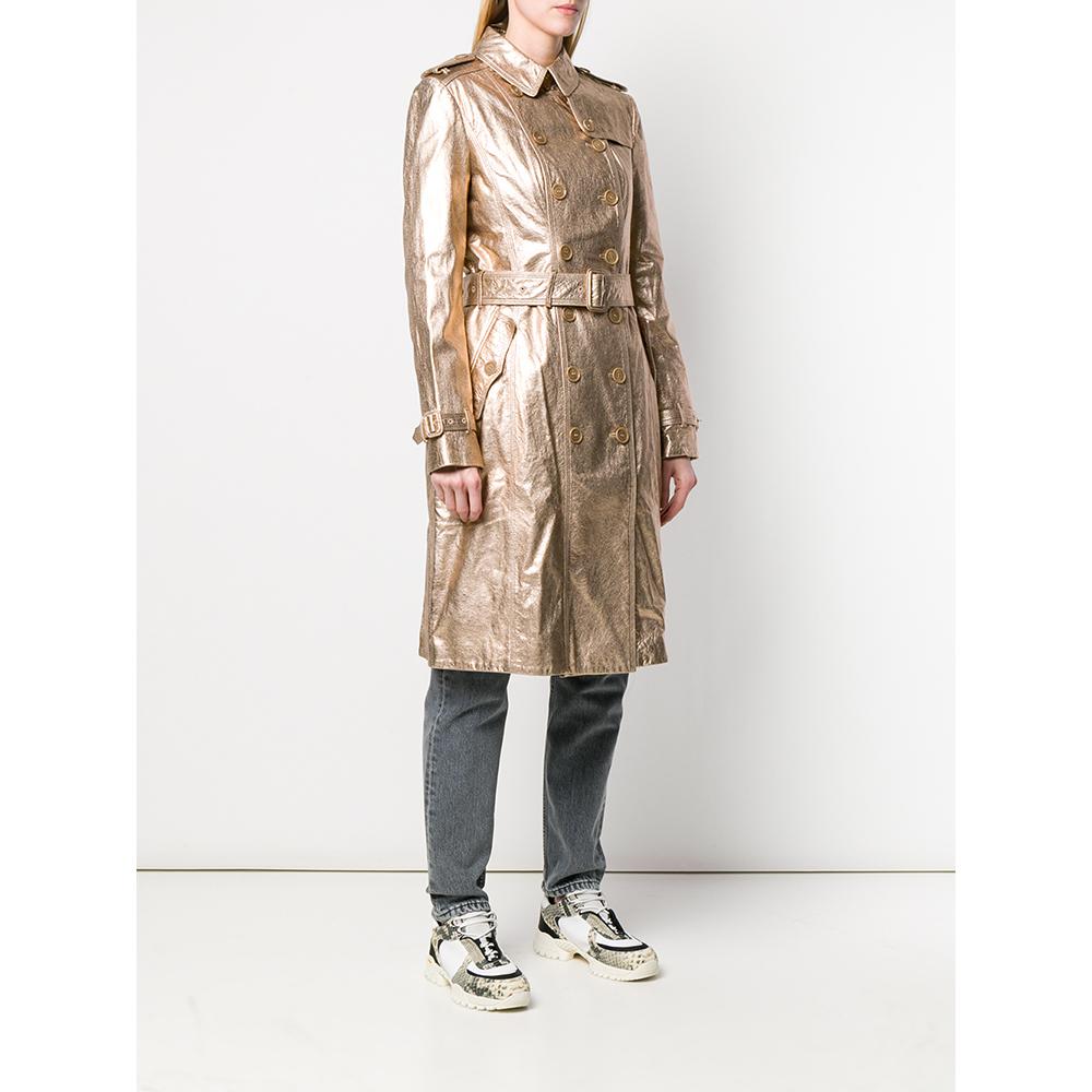 Burberry golden leather trench coat. Classic collar, double-breasted closure with logoed buttons and metal hooks. Windbreak flap, shoulder tabs with button, rain flap on the back. Long sleeves and cuffs with strap. Flap pockets and belt at the