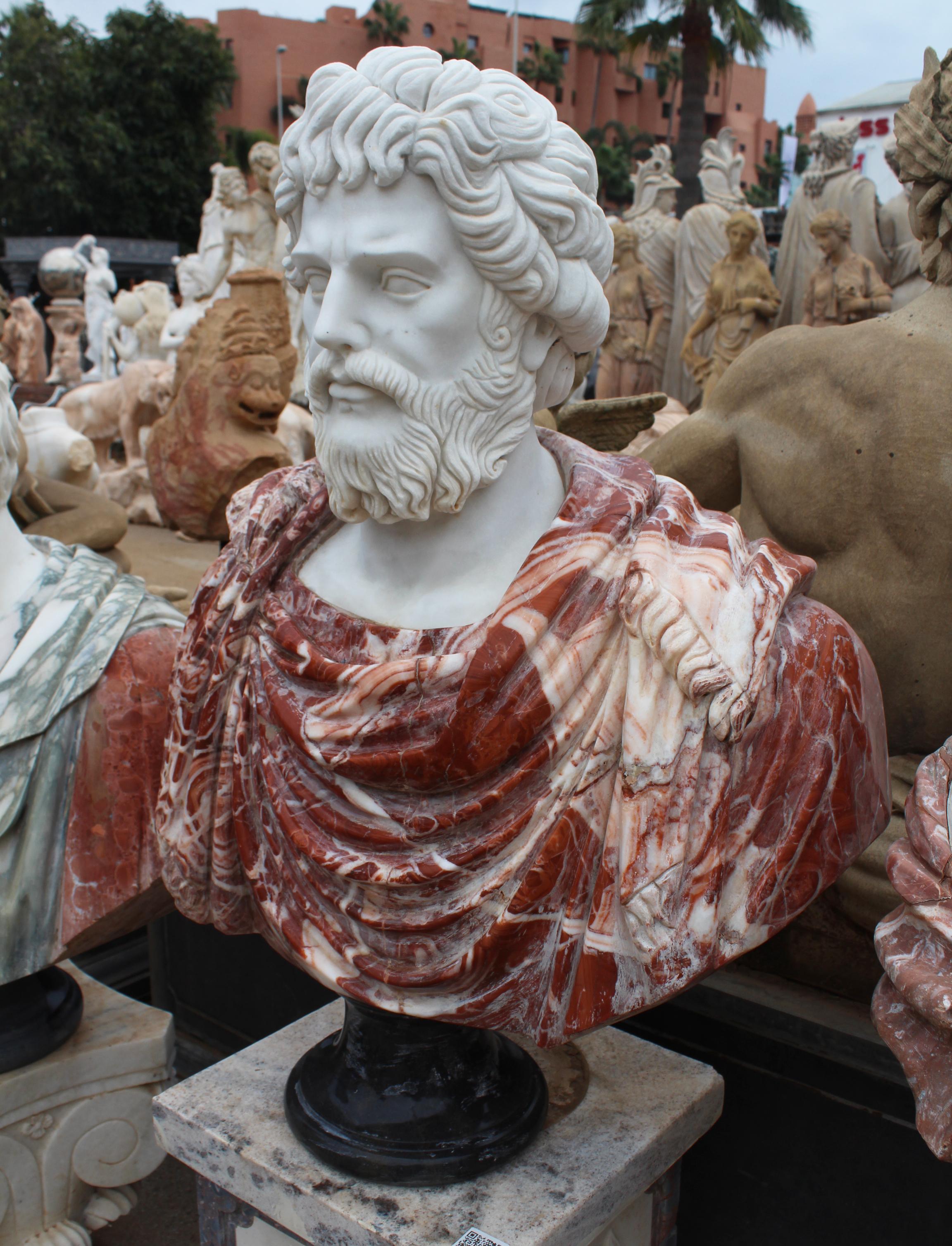 buste romain des années 1990, sculpté à la main par des artisans utilisant du marbre blanc de Carrara pour la tête et du rouge d'Alicante pour la toge, où les veines blanches donnent du mouvement et du réalisme au tissu. Base ronde simple en marbre