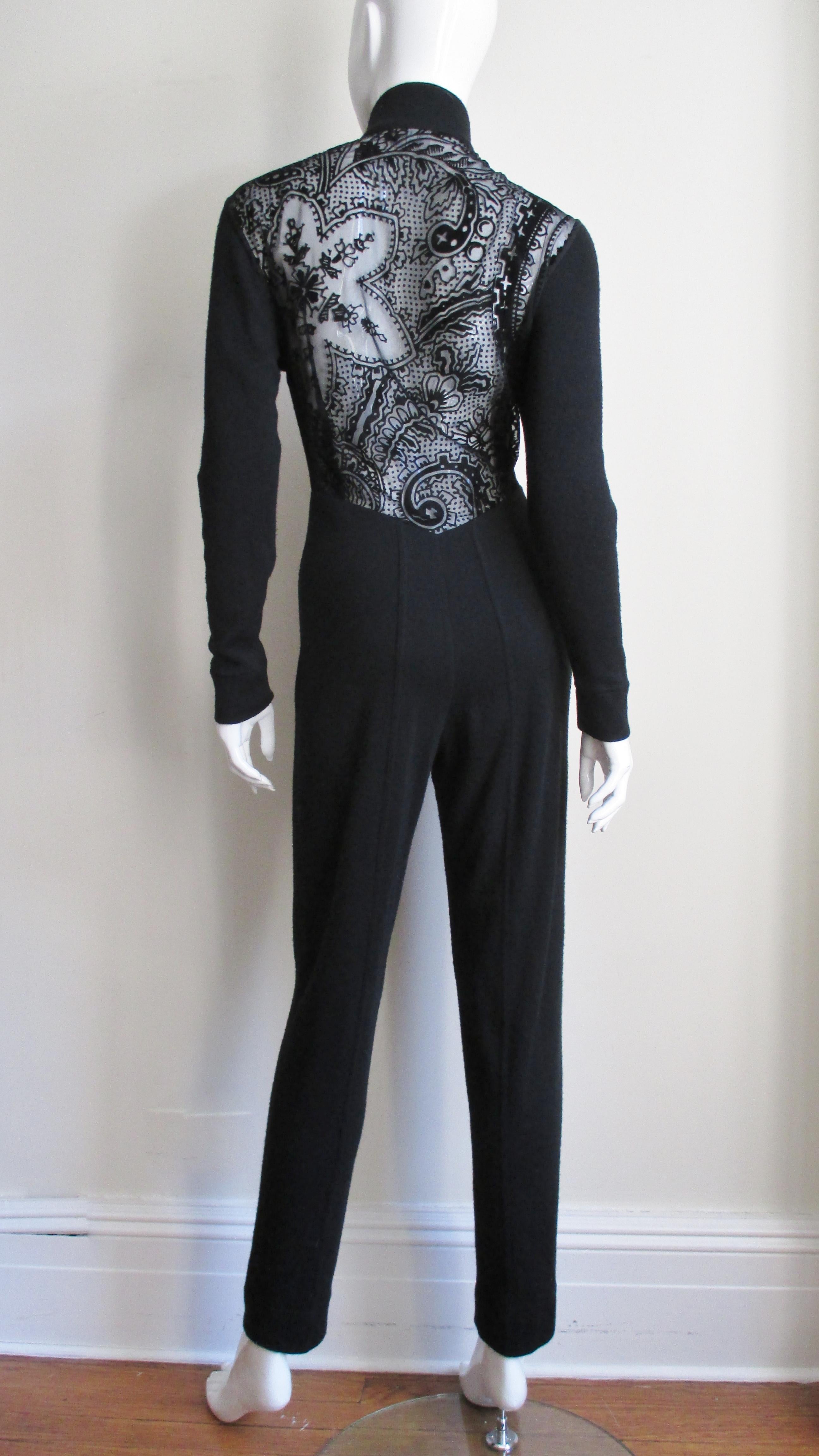 A fabulous black wool jersey catsuit jumpsuit from Byblos.  It is fitted with long sleeves, a stand up collar and a front zipper. The back is fabulous, sheer black with a flocked lace pattern.
Fits size Small, Medium.

Bust  34