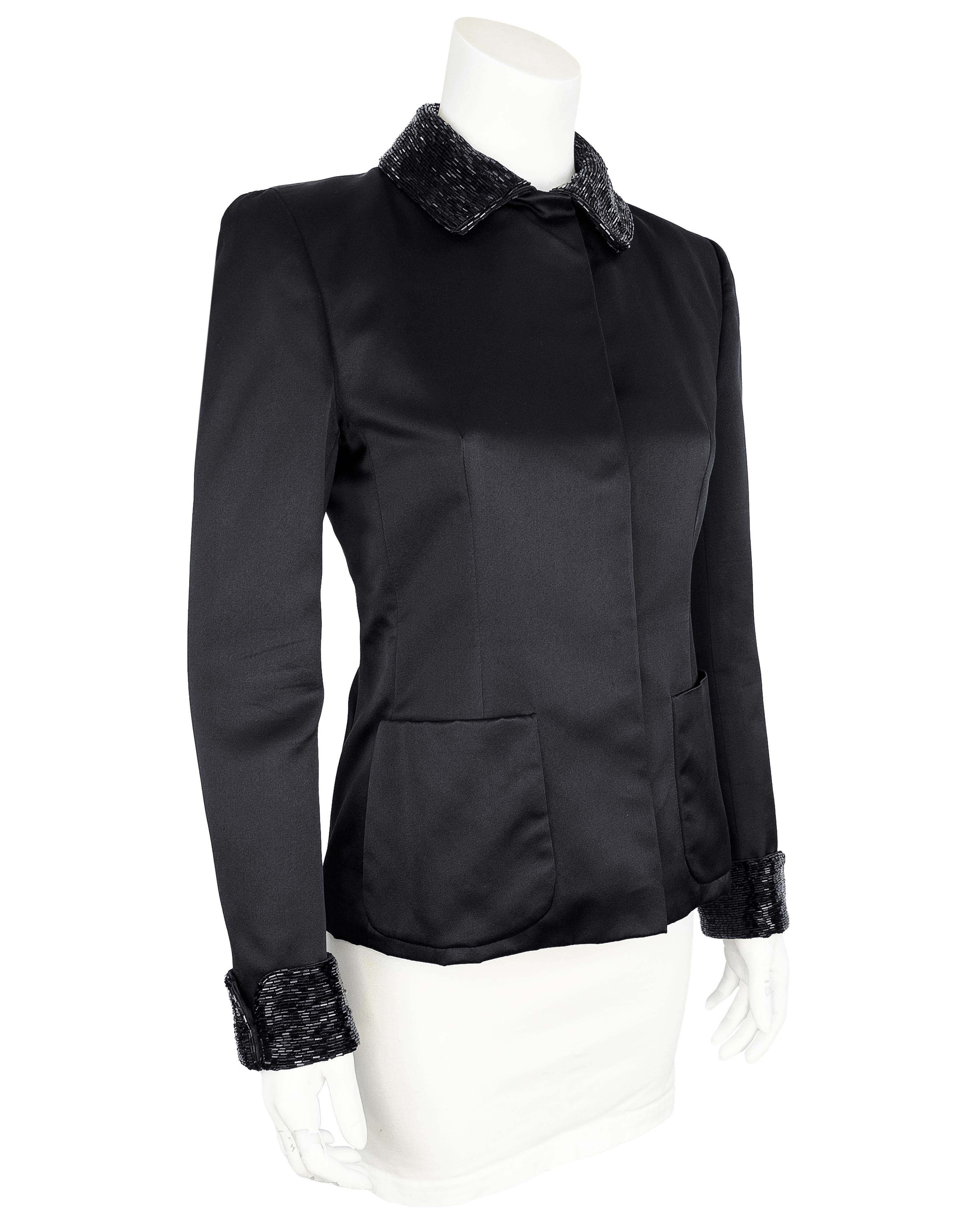 Eleva il tuo guardaroba con questa intramontabile giacca anni '90 di Calvin Klein, un'elegante miscela di design minimalista e dettagli di lusso. Raso di seta nero con colletto e polsini con perline, che aggiungono un tocco di opulenza e intrigo