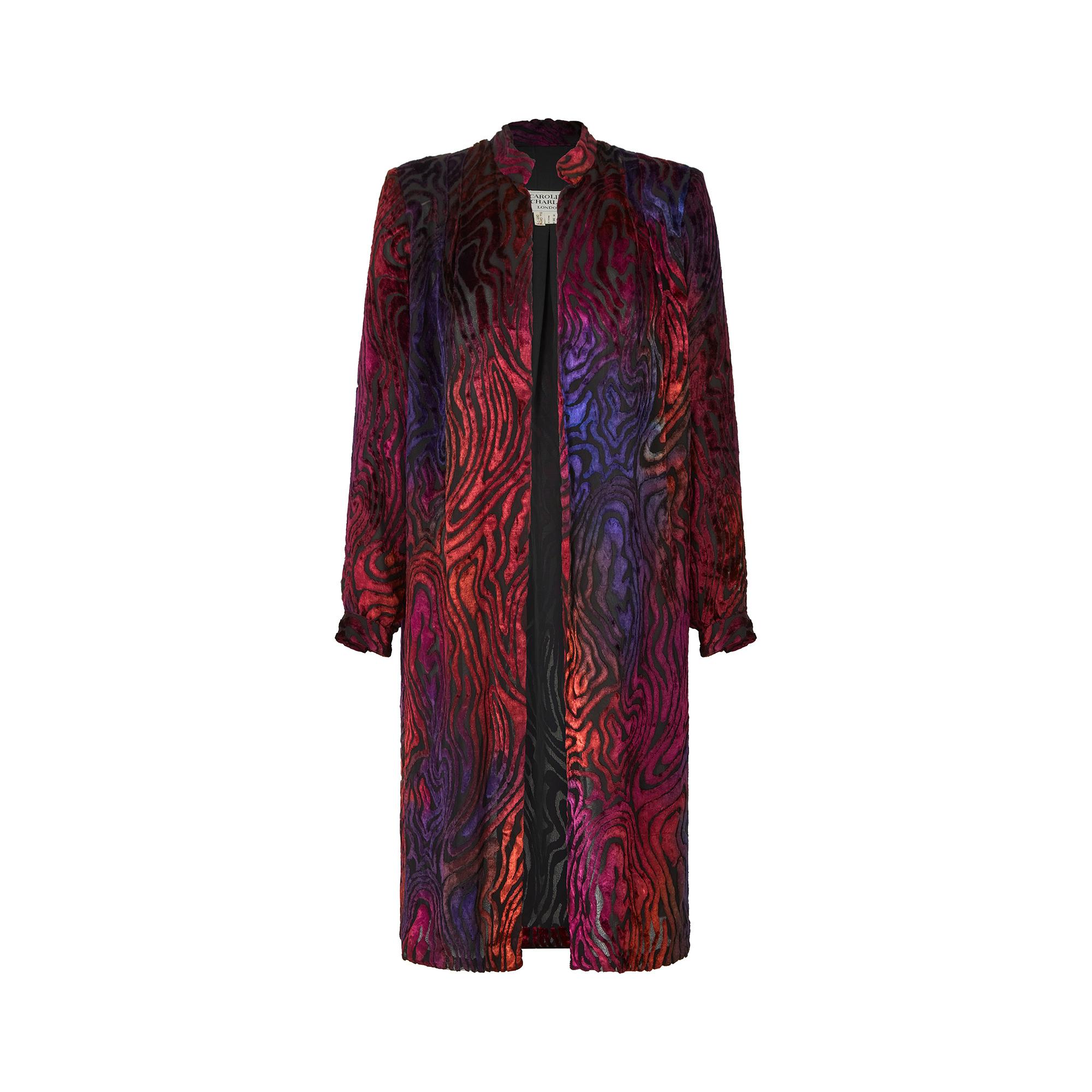 This is a striking Caroline Charles burnout velvet silk jacket, complete with vibrant autumnal colours for the colder seasons. It is cut in a loose, flowing shape with a simple high neck collar, and has draped, loose sleeves which gather at the cuff