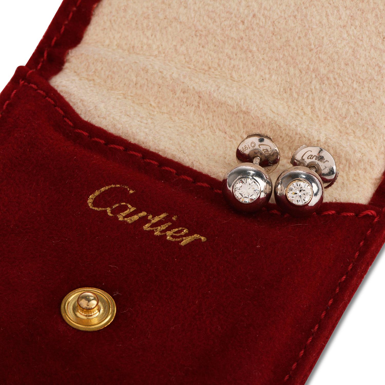 These elegant Cartier diamond stud earrings are crafted in solid 18-karat white gold, weighing 6.6 grams and measuring 8mm in diameter. Centered with a pair of bezel-set round cut diamonds, weighing approximately, 0.60 carats, graded E-F color and