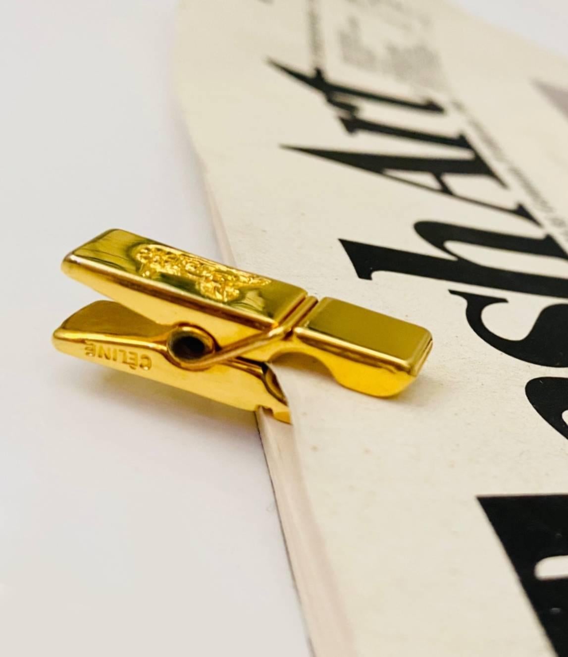 CELINE peg tie paper clip/ bookmarker in gold tone metal. featuring makers carriage CELINE on both sides of peg 

Condition: vintage, 1990s, excellent 

Dimensions: 3 cm x 1 cm
