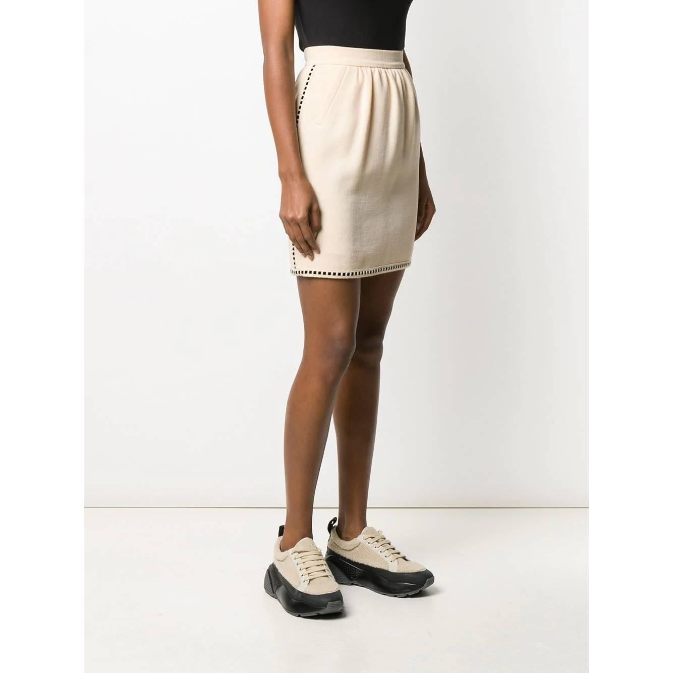 A.N.G.E.L.O. Vintage - ITALY
Chanel beige wool miniskirt with black braided ribbon. High-waisted model with decorative pleats. Front welt pockets and back fastening with zip and hooks.

Years: 90s

Made in France

Size: 36 FR

Flat