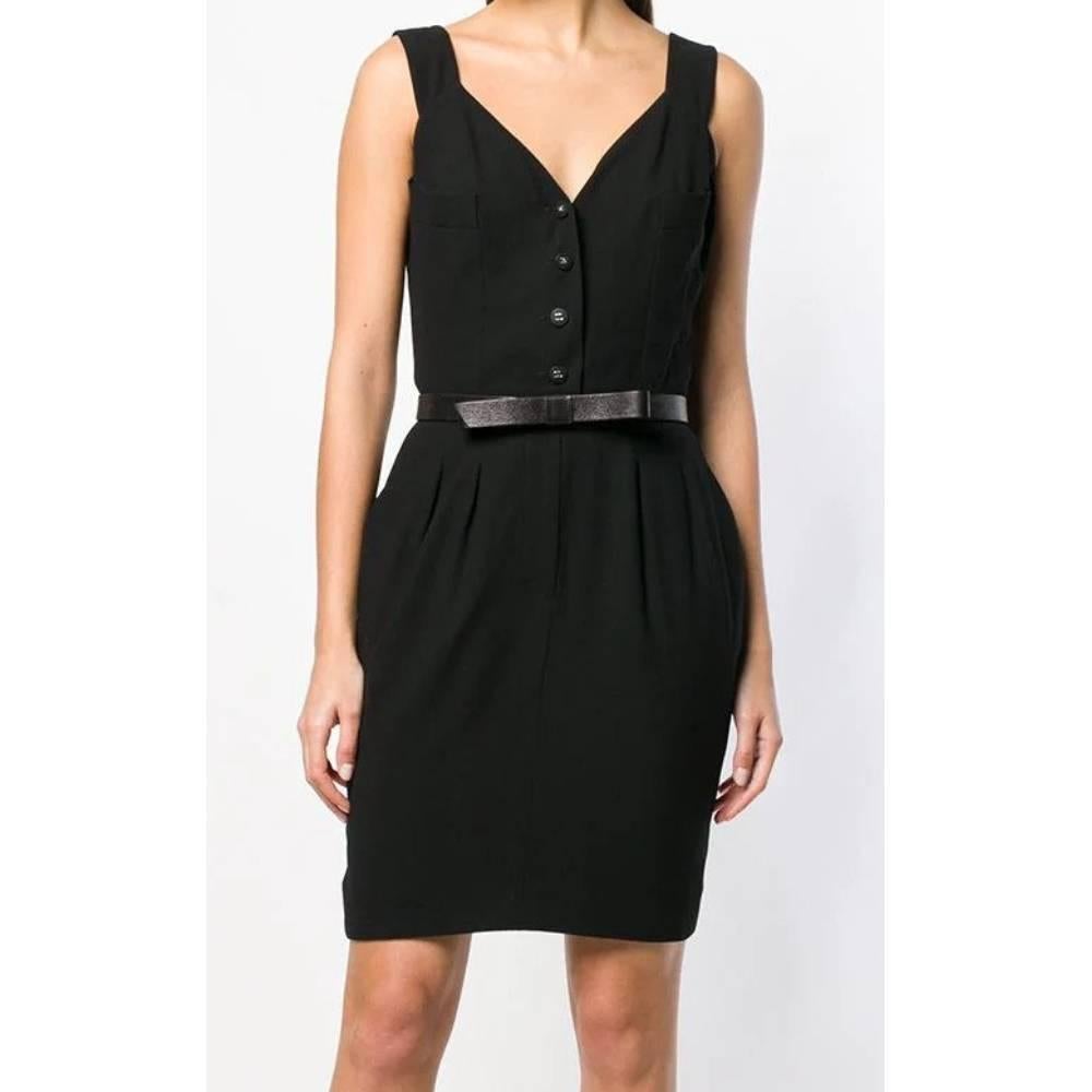 Short black mini dress Chanel with V-neck and logoed buttons, shoulder straps, belt and pleats at the waist, fake pockets with flap and button on the back

Years: 1996

Made in France

Size: 42 IT

Linear measures

Height: 95 cm
Bust: 47 cm 
Waist: