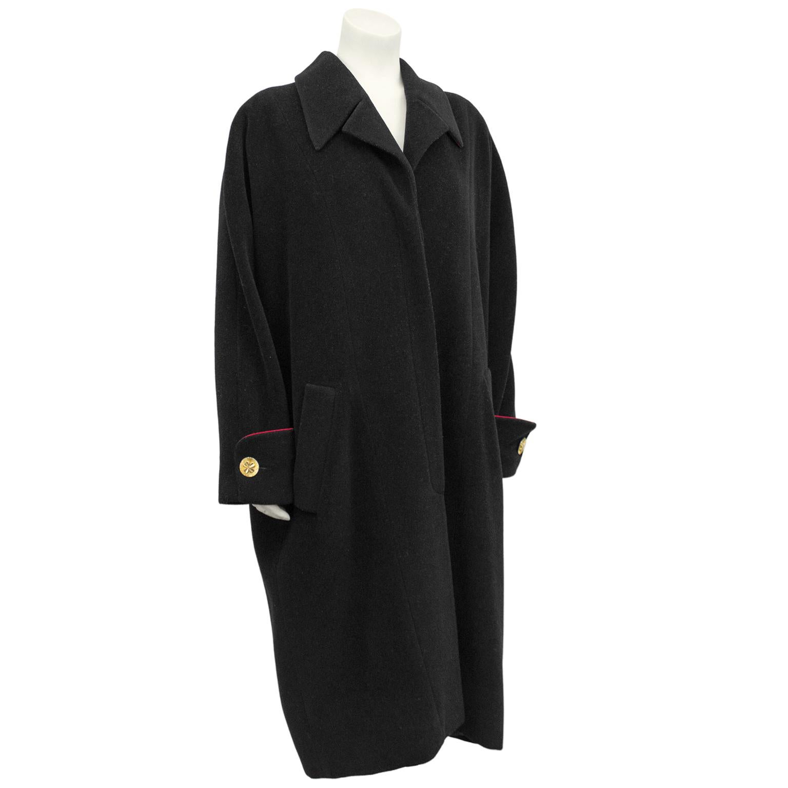 1990s Chanel black wool oversized cocoon coat with red piping on large French cuff. Classic oversized drop shoulder slouchy look that is chic on any shape and height. Contrasting red lining/trim throughout. Large gold buttons with four leaf clover