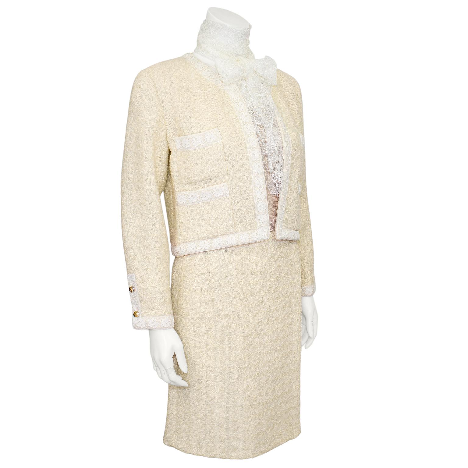Stunning Chanel suit from the 1990s. Classic in shape and style with white lace complimenting the cream boucle beautifully. The cropped, boxy, collarless jacket with four patch pockets sits open with lace trim and small dome shaped lucite and gilt