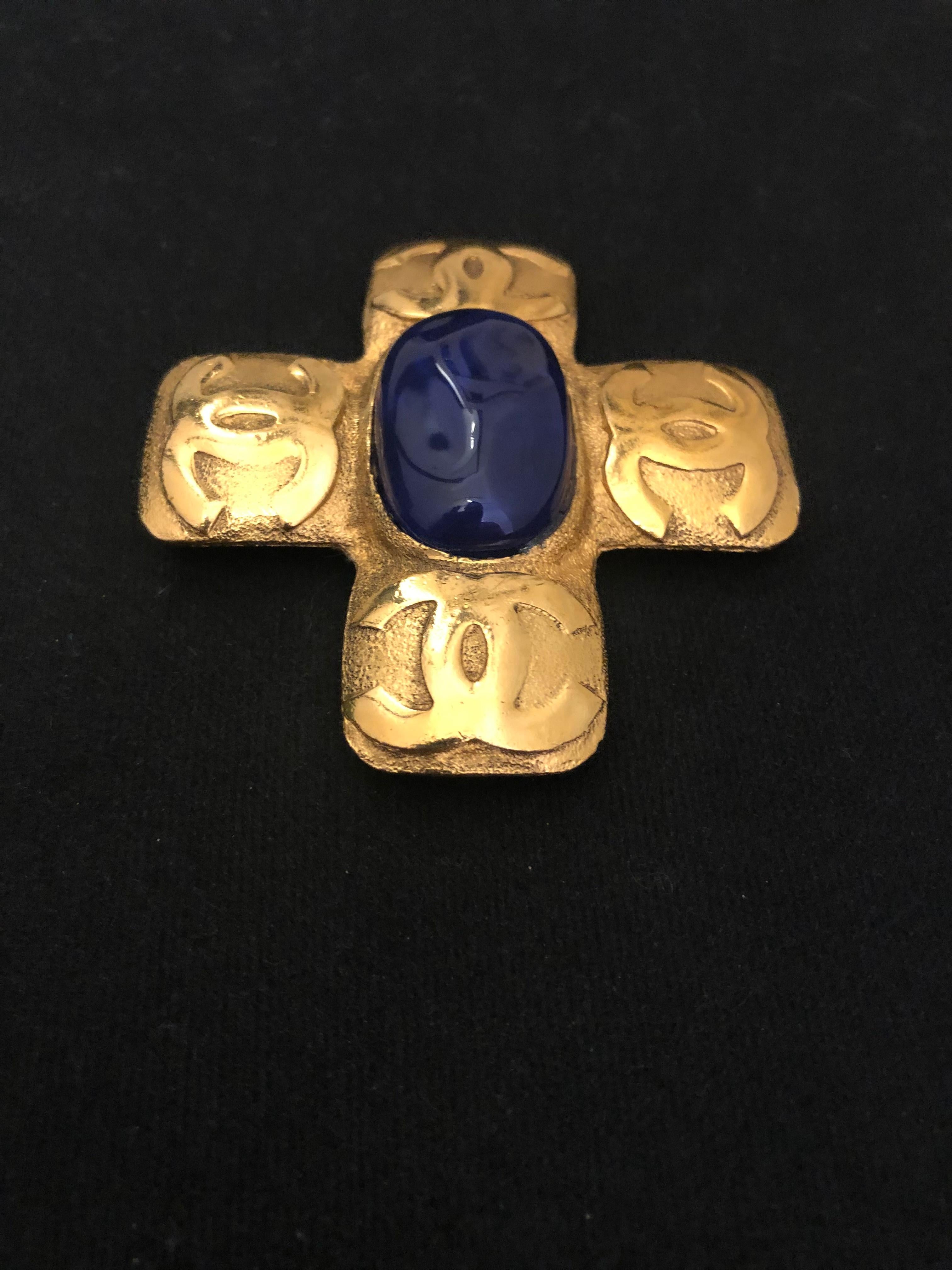 Early 1990s Chanel gold toned brooch featuring a cross decorated with four CC logos and centered a blue Gripoix. Stamped CHANEL 2 9 made in France. Measures approximately 6.7 x 6.2 cm. Comes with box. 

Condition: Minor signs of wear. Slight bent on