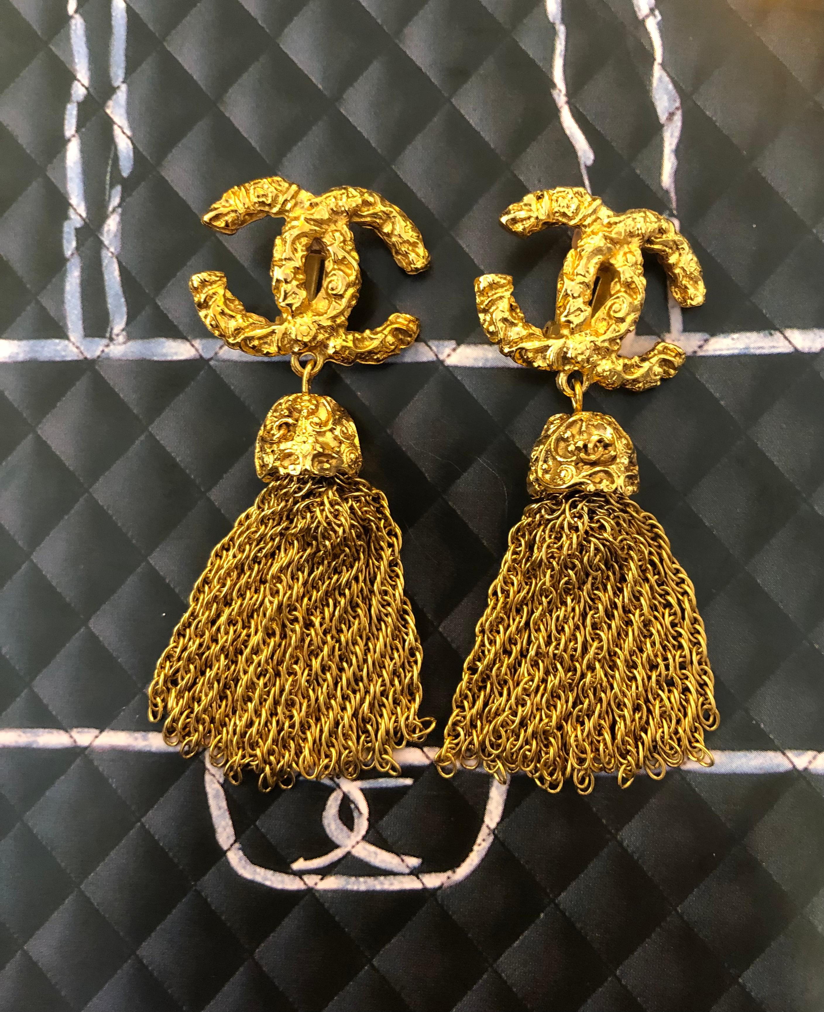 1990s Chanel gold toned clip-on earrings featuring gold toned chain tassels and textured CC logo. Clip on style. Stamped Chanel 93A made in France. Measures 2.5 x 6 cm. Come with box. 

Condition - Minor signs of wear. Generally in good condition. 