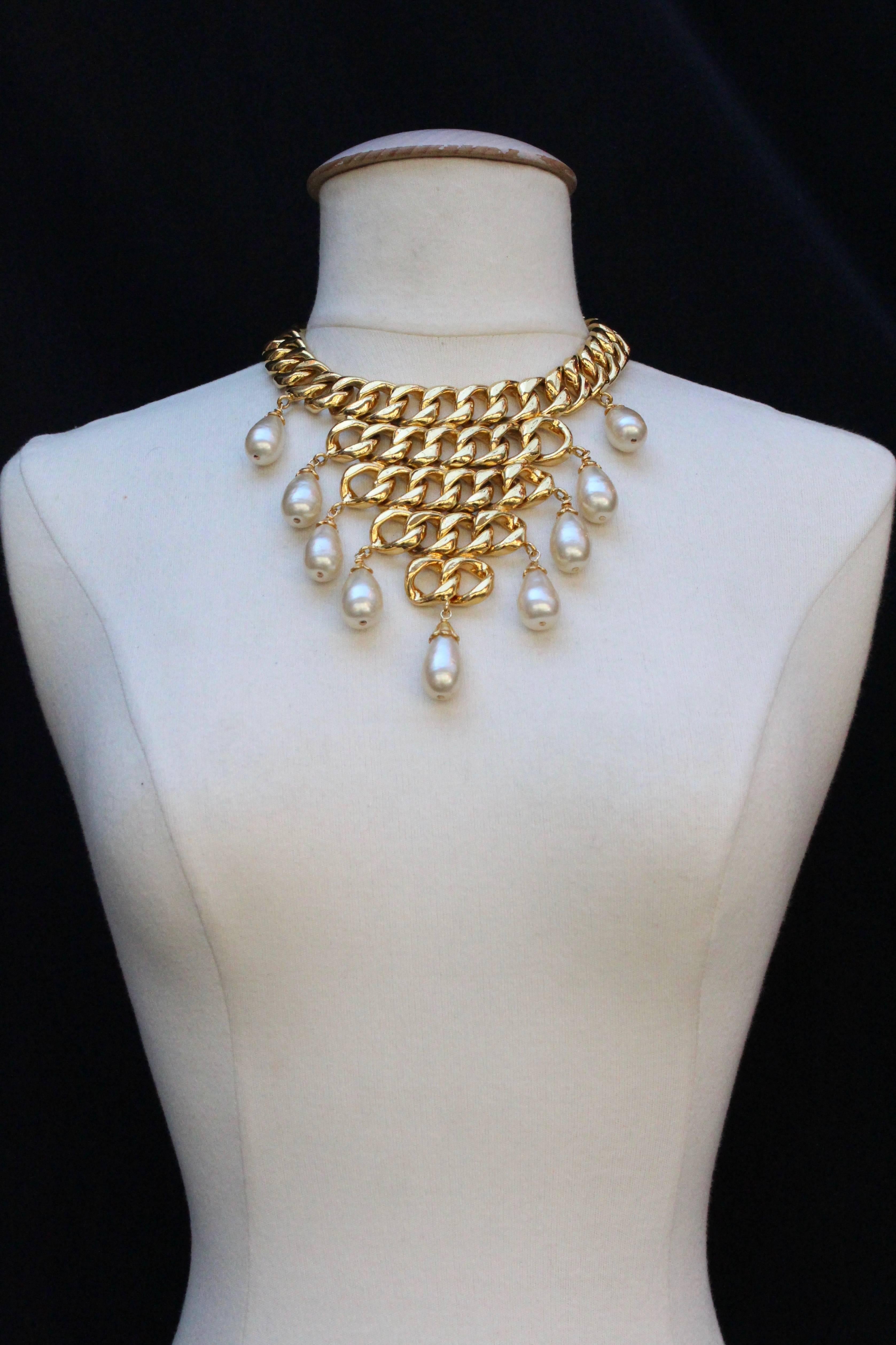 CHANEL (Made in France) Stunning iconic choker composed of five strands of wide gilded metal curb chain. On each strand are fixed two pearly drops, then a single one in the center of the necklace.

Hook and eye clasp with a small chain for length