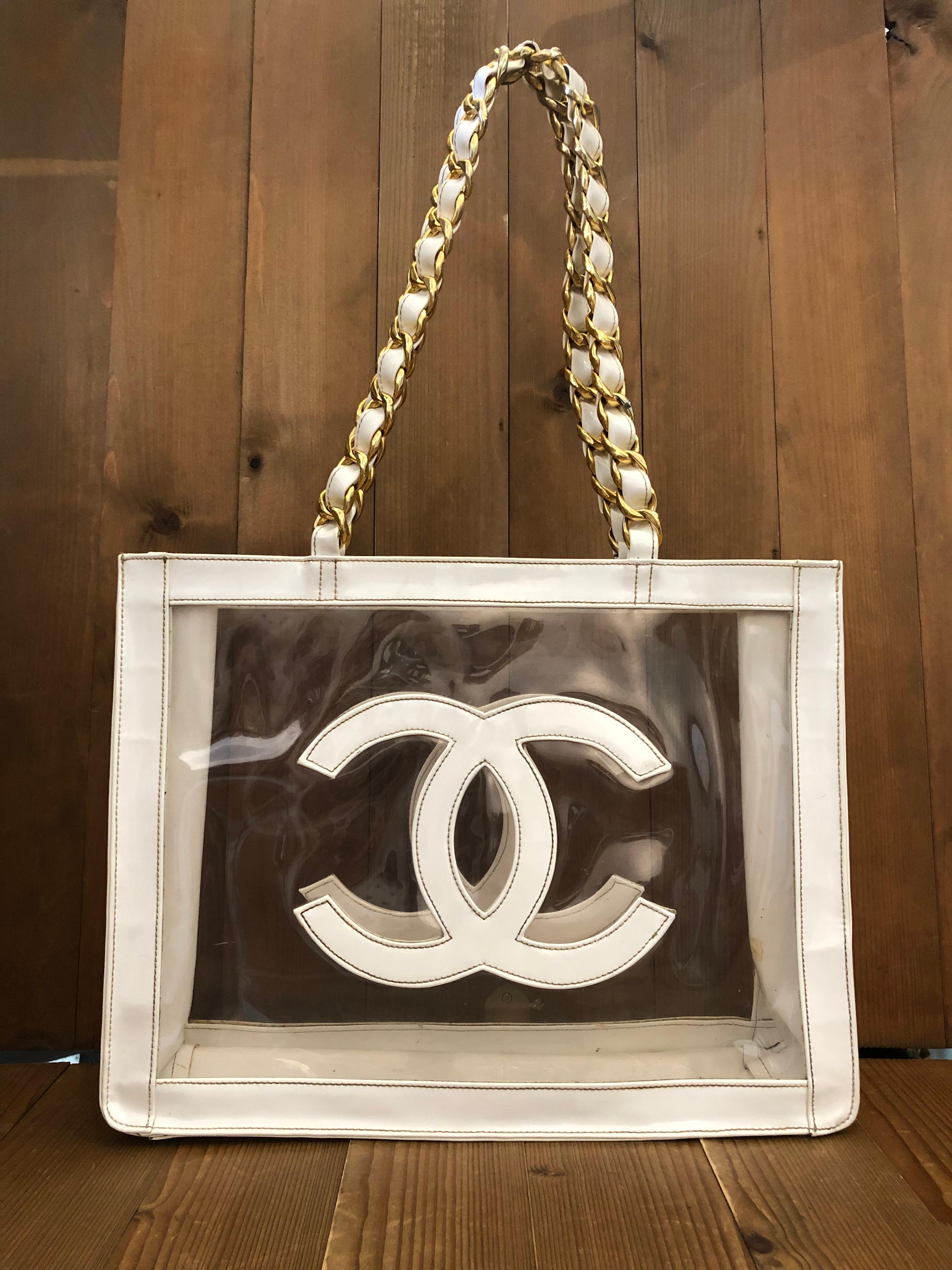 This vintage CHANEL jumbo chain tote is crafted of clear and off white vinyl featuring a massive CC logo on each side with sturdy gold toned chain link shoulder straps interlaced with off white vinyl. Made in France. Measures 16 x 12.25 x 4.5 inches