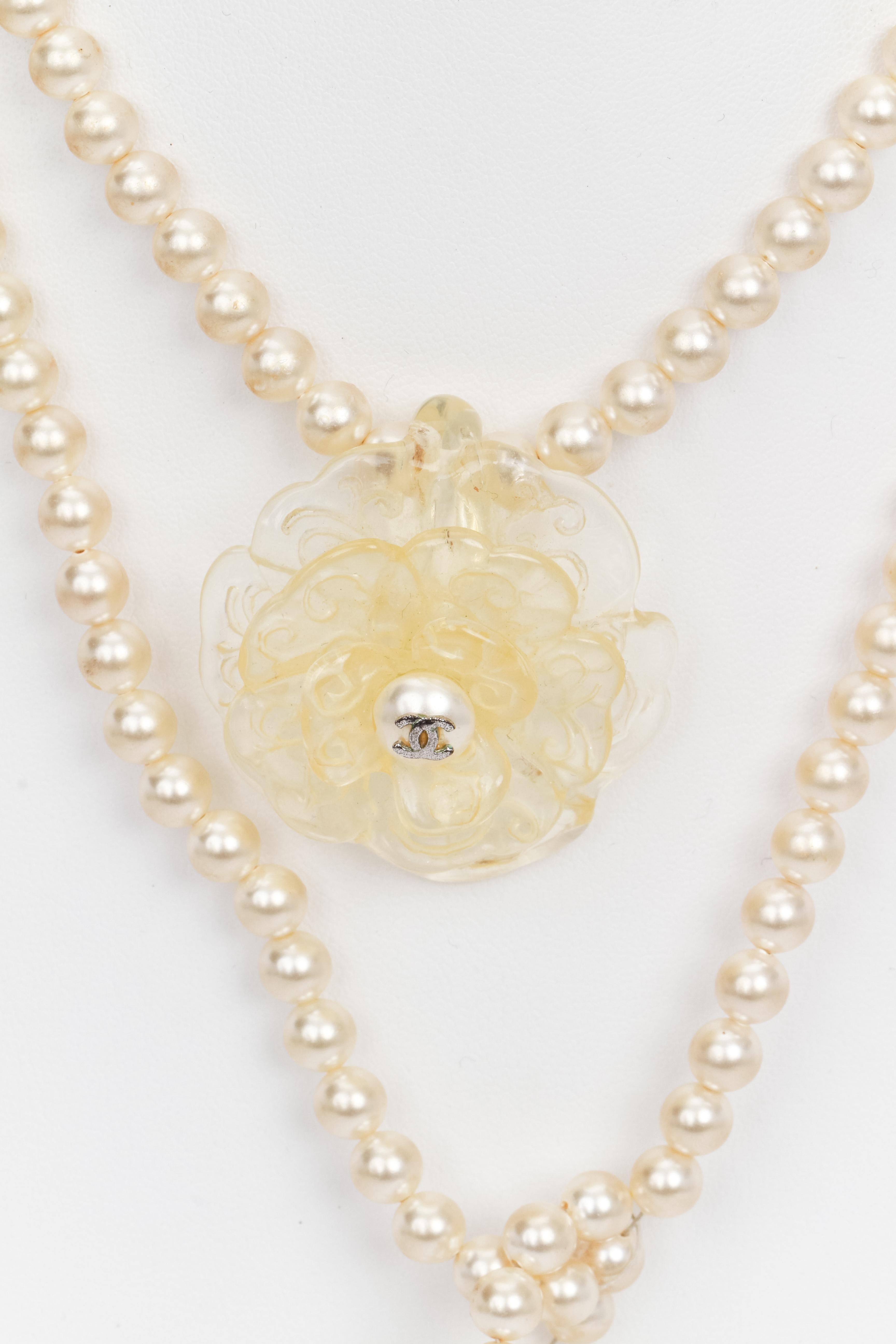 Chanel long open necklace with pearls, centering a lucite camellia flower with pearl and CC logo. Lucite leaves finials at both ends. Create your own way to wear it. 1990s