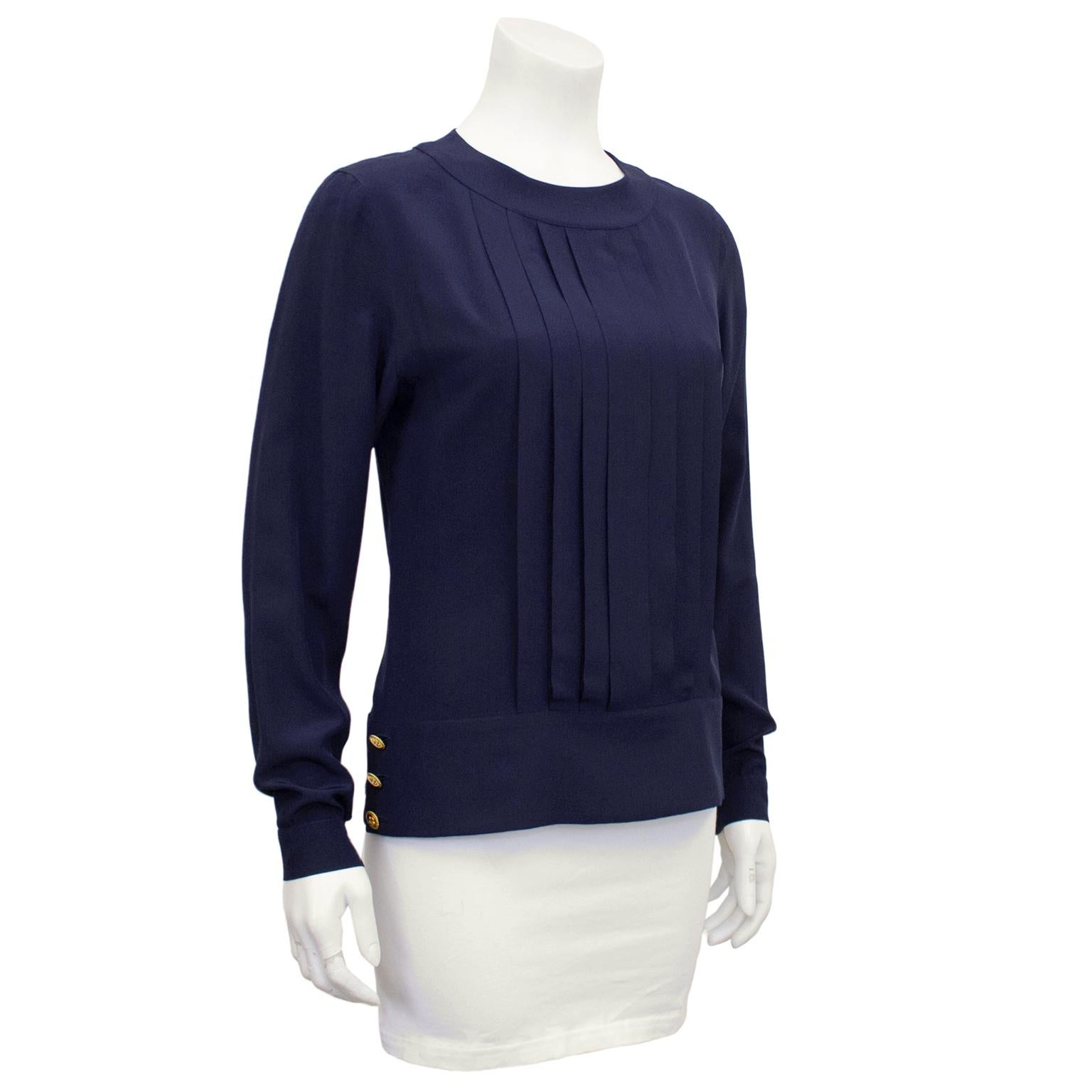 1990s Chanel navy blue silk blouson top. Crew neckline with flat pleated front. Oversized waistband and single flat pleat up centre back, covering the tiny navy buttons. Two gold Chanel logo buttons at cuffs, 3 each at drop waist and 1 at nape of