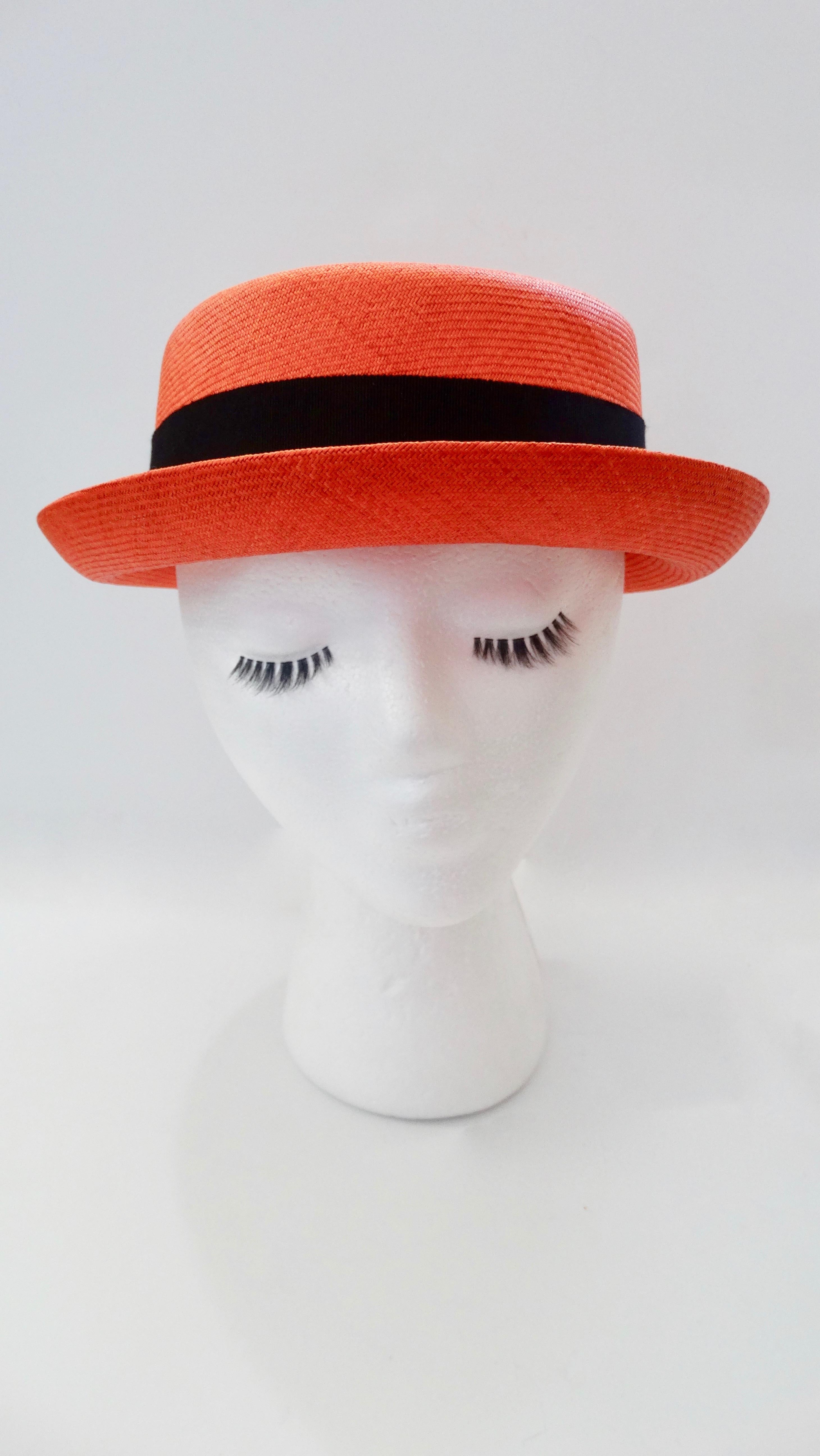 Treat yourself with a piece of Chanel! Circa 1990s, this boater hat is made of orange/red straw and features a black grosgrain ribbon around the base of the crown. From brunch to vacations, to lounging by the pool, this hat is perfect! Made in