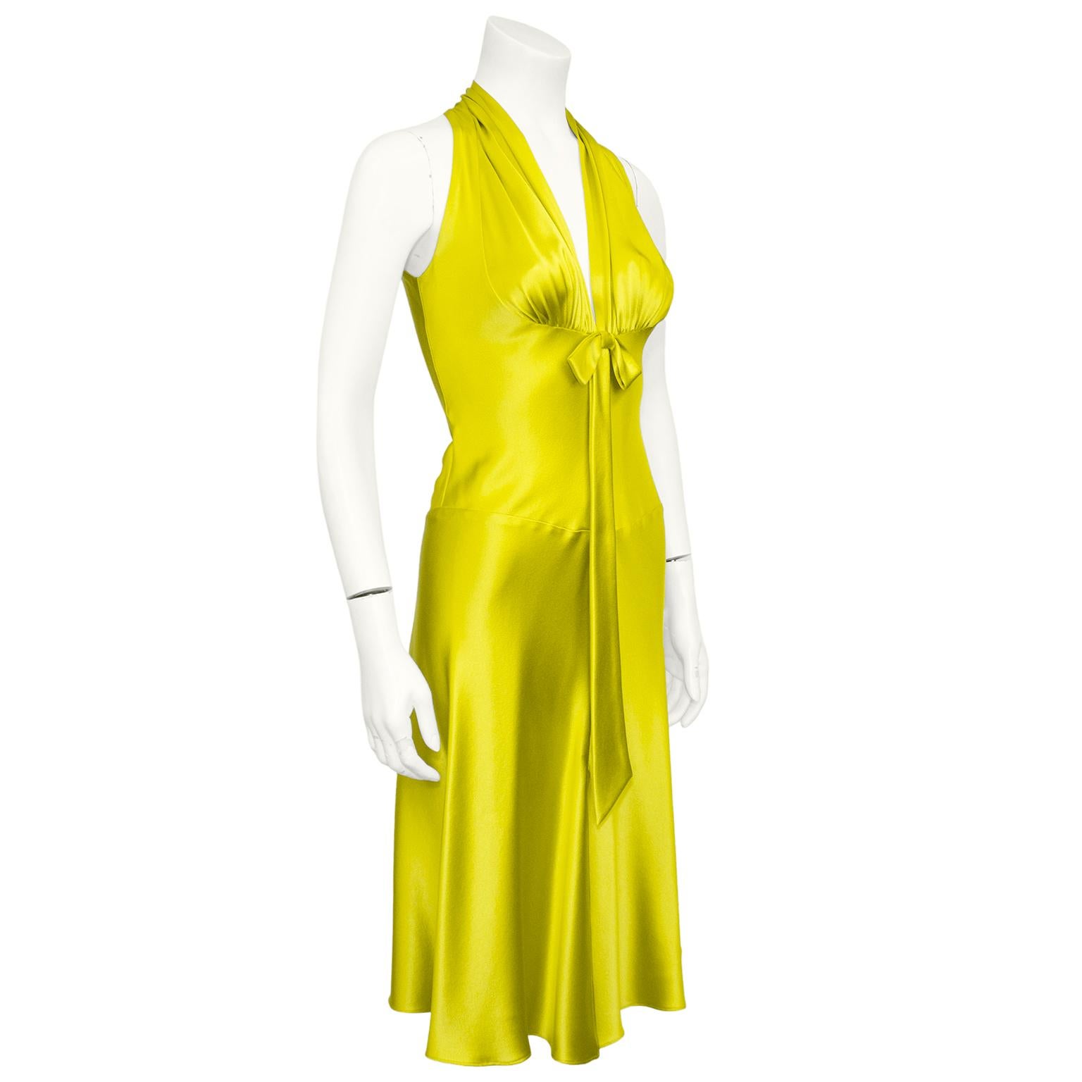 Stunning & sexy silk chartreuse satin dress from the 1990s. Deep v neckline with rounded ruching at bust and bow detail. The silk skims the body with a drop waist and flows into a mid length skirt. Small slit at centre front seam that adds movement