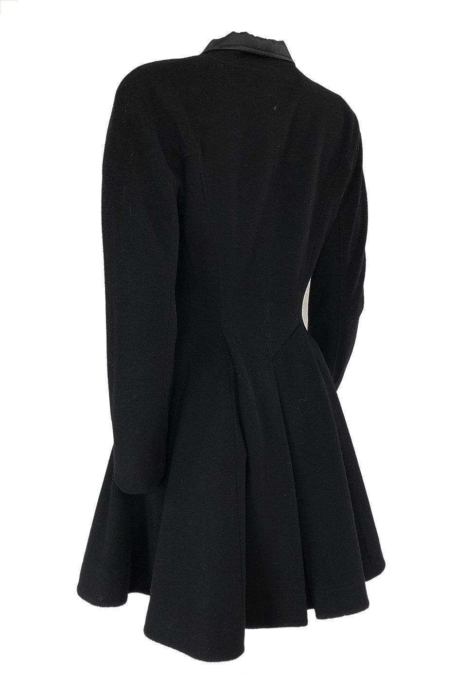 This is a wonderful little black coat by the Dior label that has a strong nod to the 1940s in the way it is cut. The top portion of the coat has lovely rounded shoulders whose seams are set to run across the shoulder and down the sleeve so there is