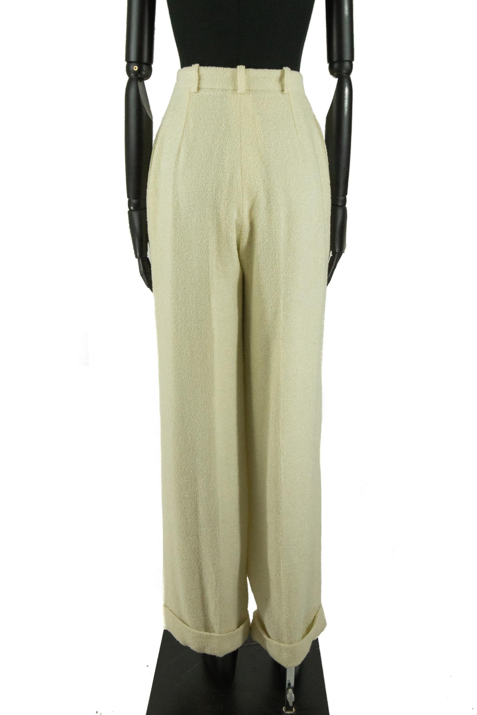 Mid 1990s Christian Dior wide leg high waisted trousers made from soft cream boucle wool, with soft pleated darts in the waistband. The trousers have straight side pockets, front creases and folded over cuffs on the bottom. The waistband has