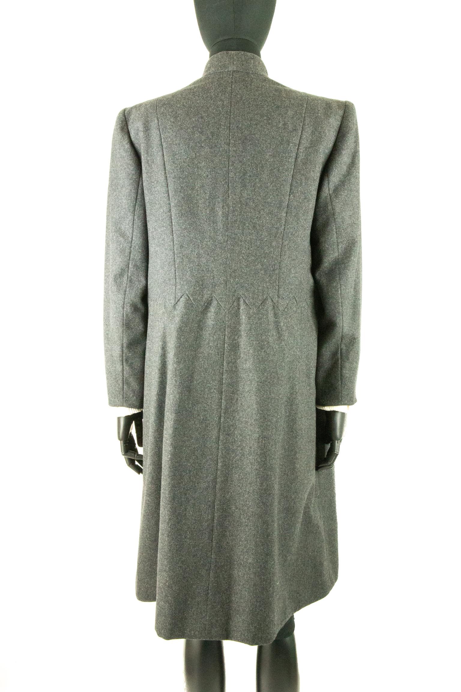 An early 1990s Christian Dior woollen mid-length coat in a charcoal grey, with princess seams on the back and front bodice. The coat has a mandarin collar and shoulder pads for additional structure. The long tapered sleeves have a detached white