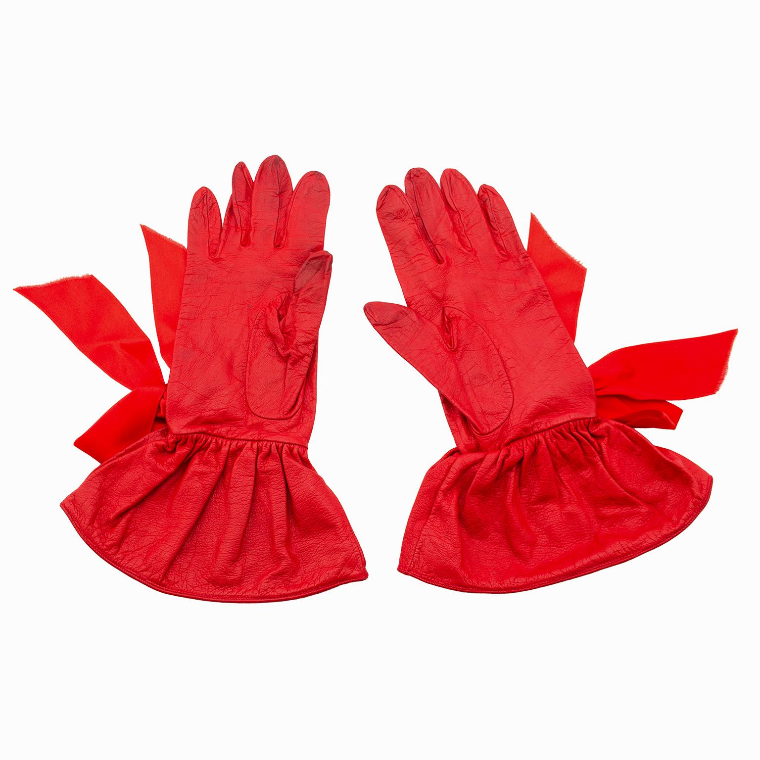 Stunning 1990s Christian Dior gloves. Supple red leather with suede interior. Gloves extend past wrist with a wide ruffle gauntlet and are embellished with large red satin bows. Matching red top stitching. Size 7 3/4. Good vintage condition - some