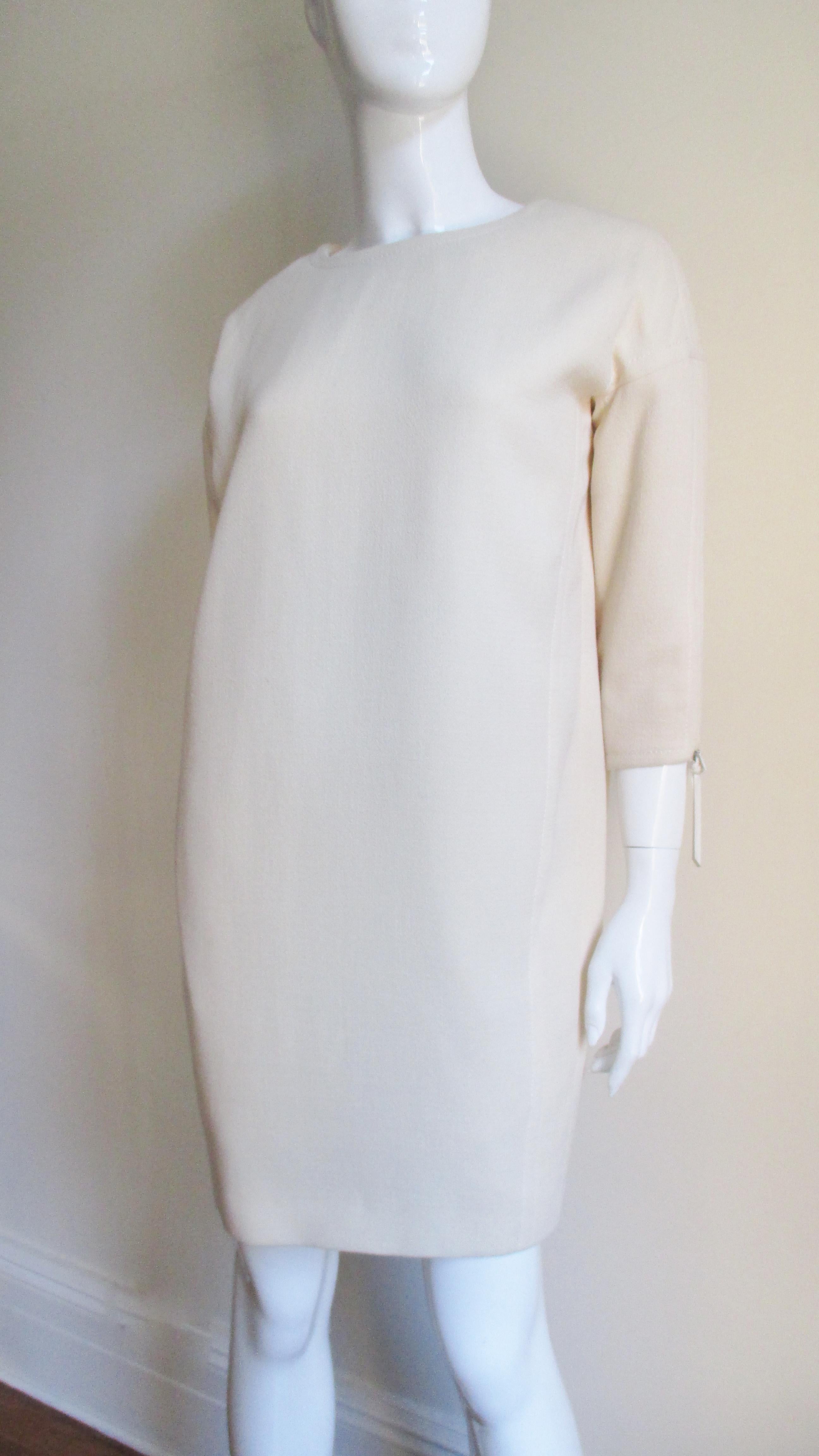 A fabulous chic dress from Christian Dior in off white wool.  It has a crew neckline, 3/4 length sleeves with matching leather pulls on their zippers and pockets in the off center front seams.  It is lined in off white silk, has top stitched seams