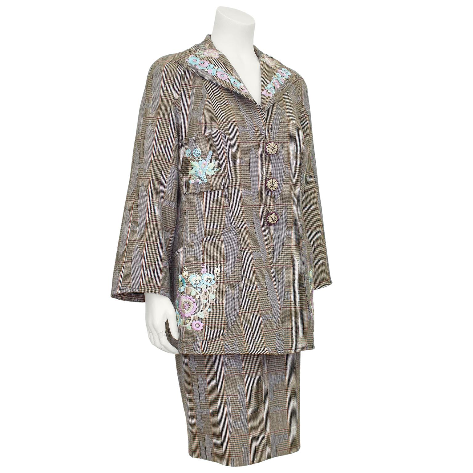 1990s Christian Lacroix tweed skirt suit with pastel floral embroidery. The long jacket is flattering and hugs the body with U shaped pockets on the hips and smaller pockets at the bust. Fastens with a placket and 3 oversized embroidered buttons at