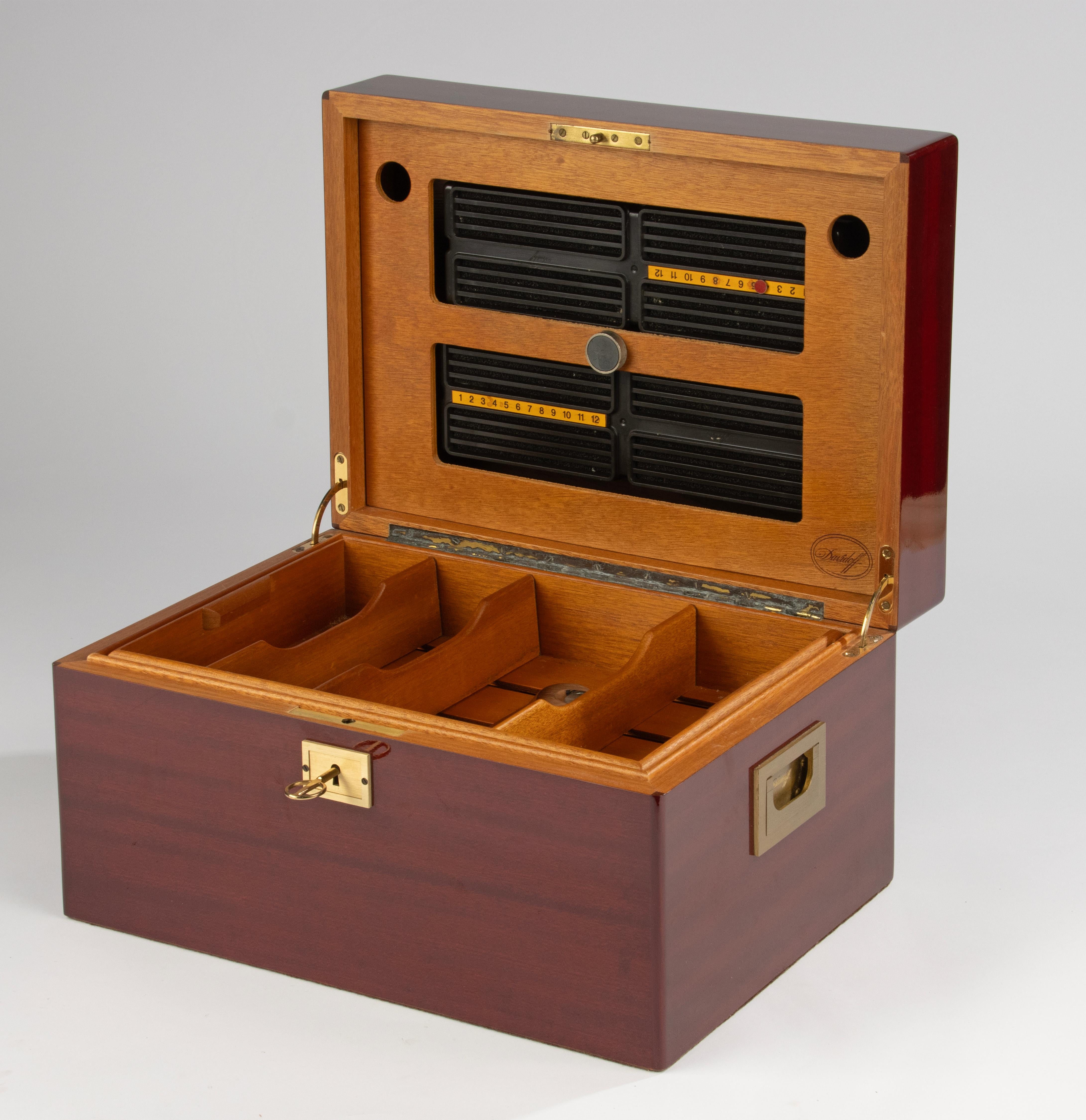 Elegant vintage Davidoff humidor, dating from the 1990s. This high-quality cigar box combines luxury craftsmanship with timeless design. The exterior is finished in a rich high-gloss mahogany, complemented by recessed solid brass handles and