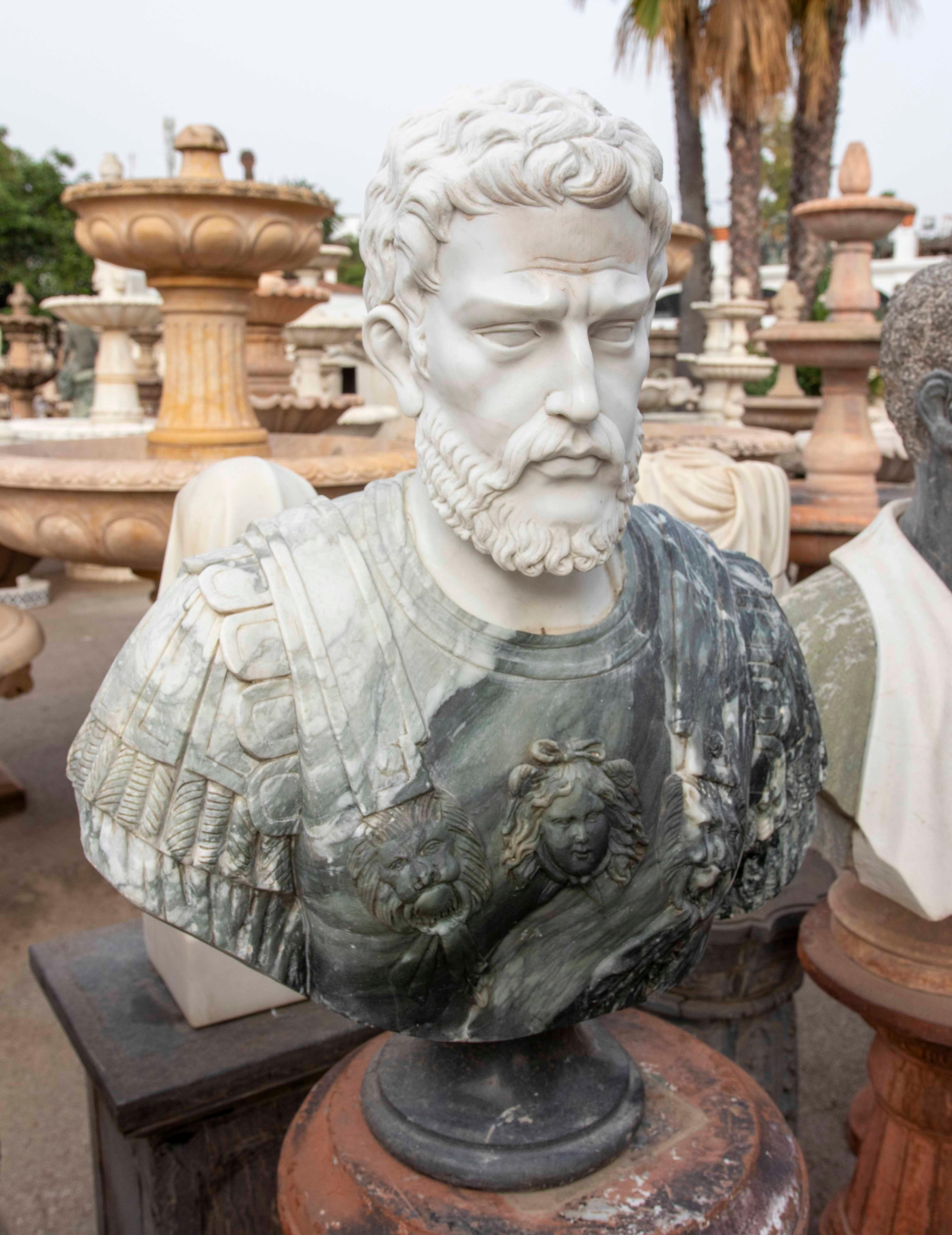 Impressionnant buste d'un empereur romain sculpté dans du marbre blanc pour le visage et veiné de vert pour l'armure. Il se distingue par les reliefs de la cuirasse, qui comprennent des têtes de lion et de Méduse finement sculptées. Le contraste des