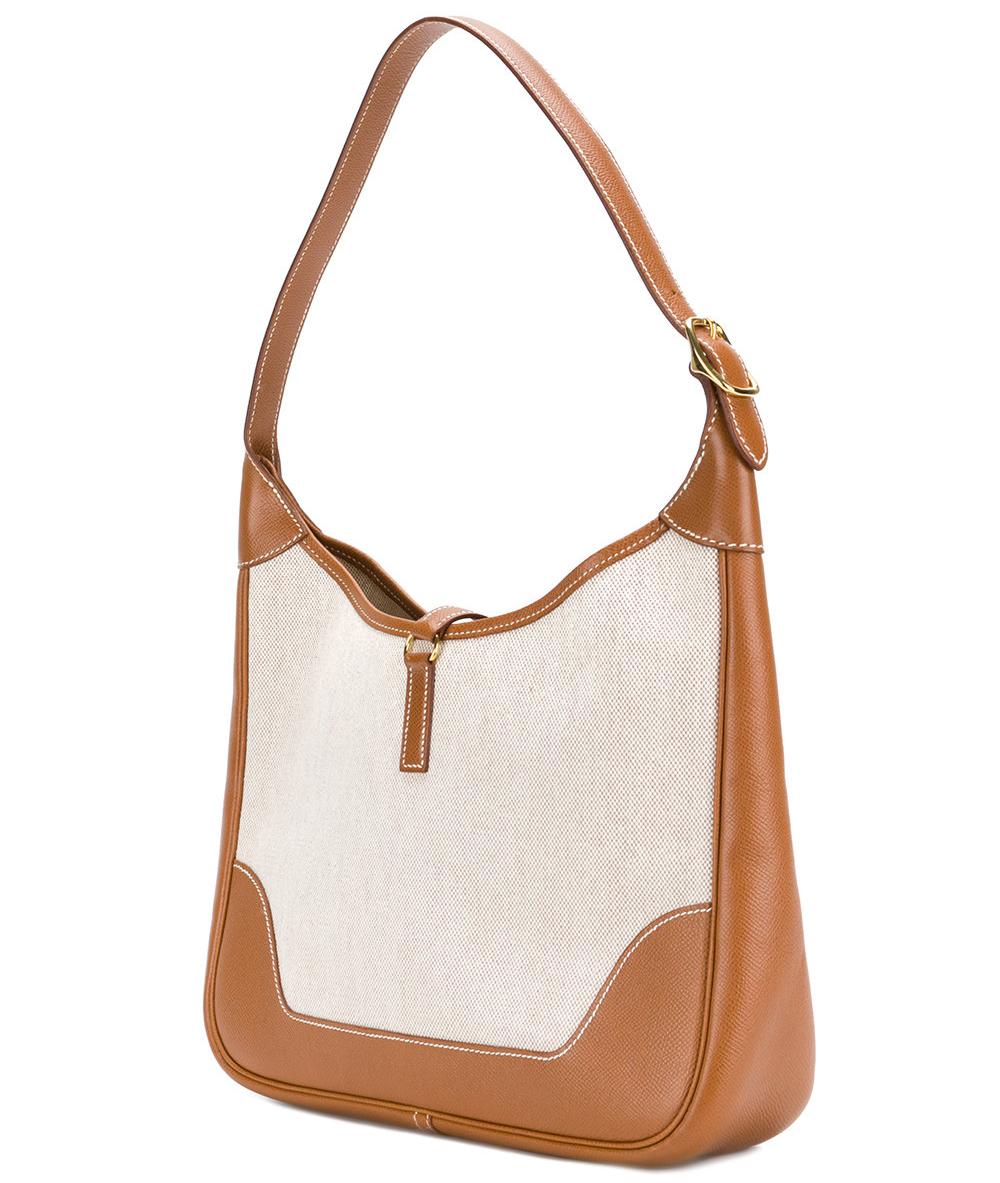 
Classy Hermès beige canvas and brown leather zipped Hobo bag. It features an adjustable shoulder strap, a lobster clasp closure, a main internal compartment, stitching details and gold-tone hardware. 
It comes with its original dustbag. According