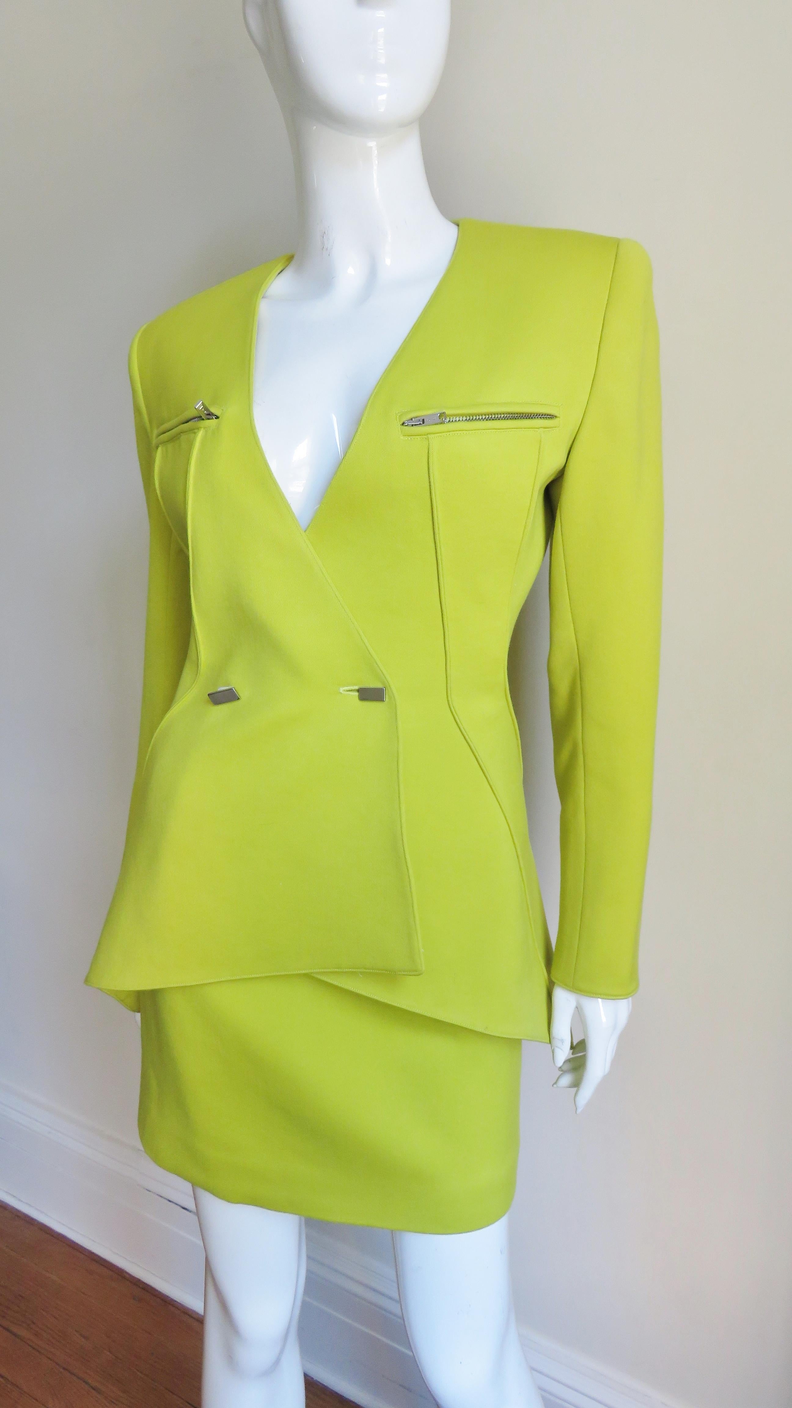A gorgeous neon yellow green wool skirt and jacket by Claude Montana. The jacket has angled vertical seaming wrapping around the waist to the back hemline which has a slight flare. It is double breasted closing with front silver metal rectangular