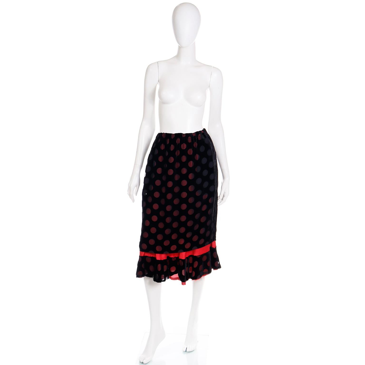 This is a fun, playful vintage Comme des Garcons skirt  in a black rayon silk blend with red and black polka dotted lining.
The top fabric has an almost velvet appearance with transparent fabric circles revealing the red and black polka dot lining.