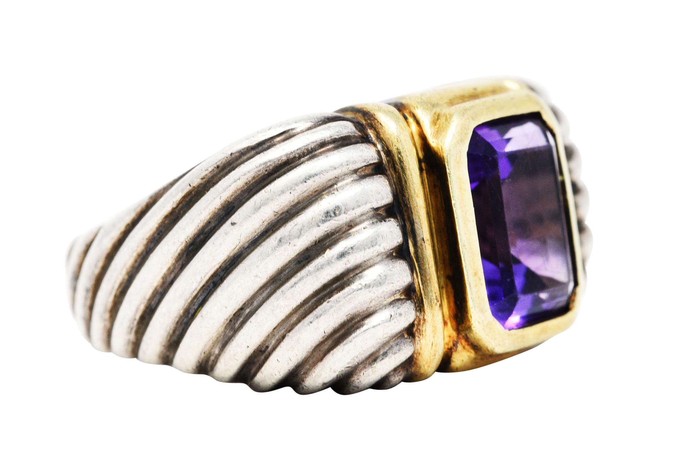 Centering an emerald cut amethyst measuring approximately 10.0 x 8.0 mm

Transparent and a saturated violetish purple in color

Bezel set in polished gold surround

Completed by cushion shoulders with classic cable design extending down the