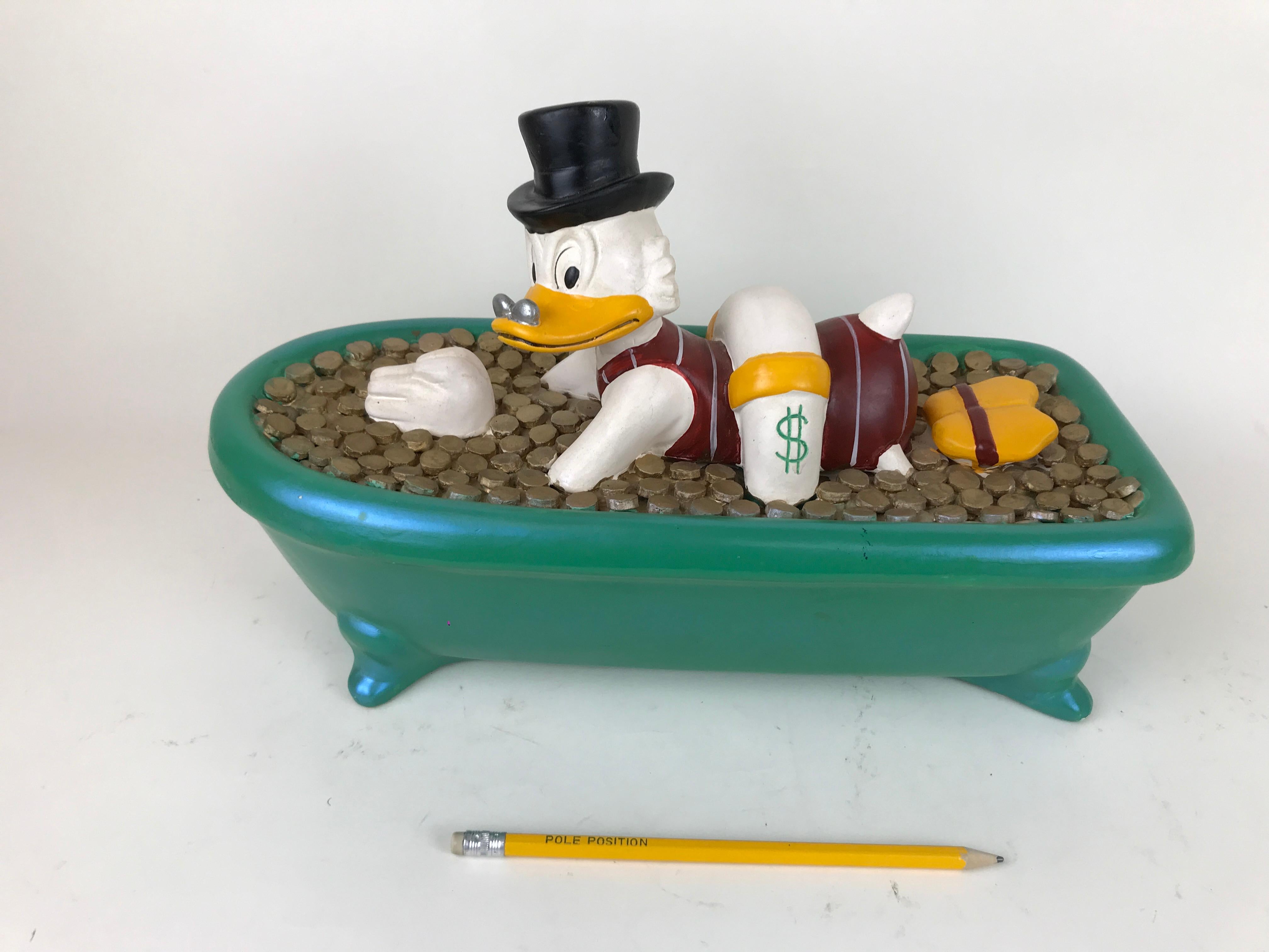 Vintage ceramic figure of Uncle Scrooge swimming in a bathtub filled with money made by Demons & Merveilles in France in the 1990s.

Marked Registered Demons & Merveilles on the side along with Disney.

     