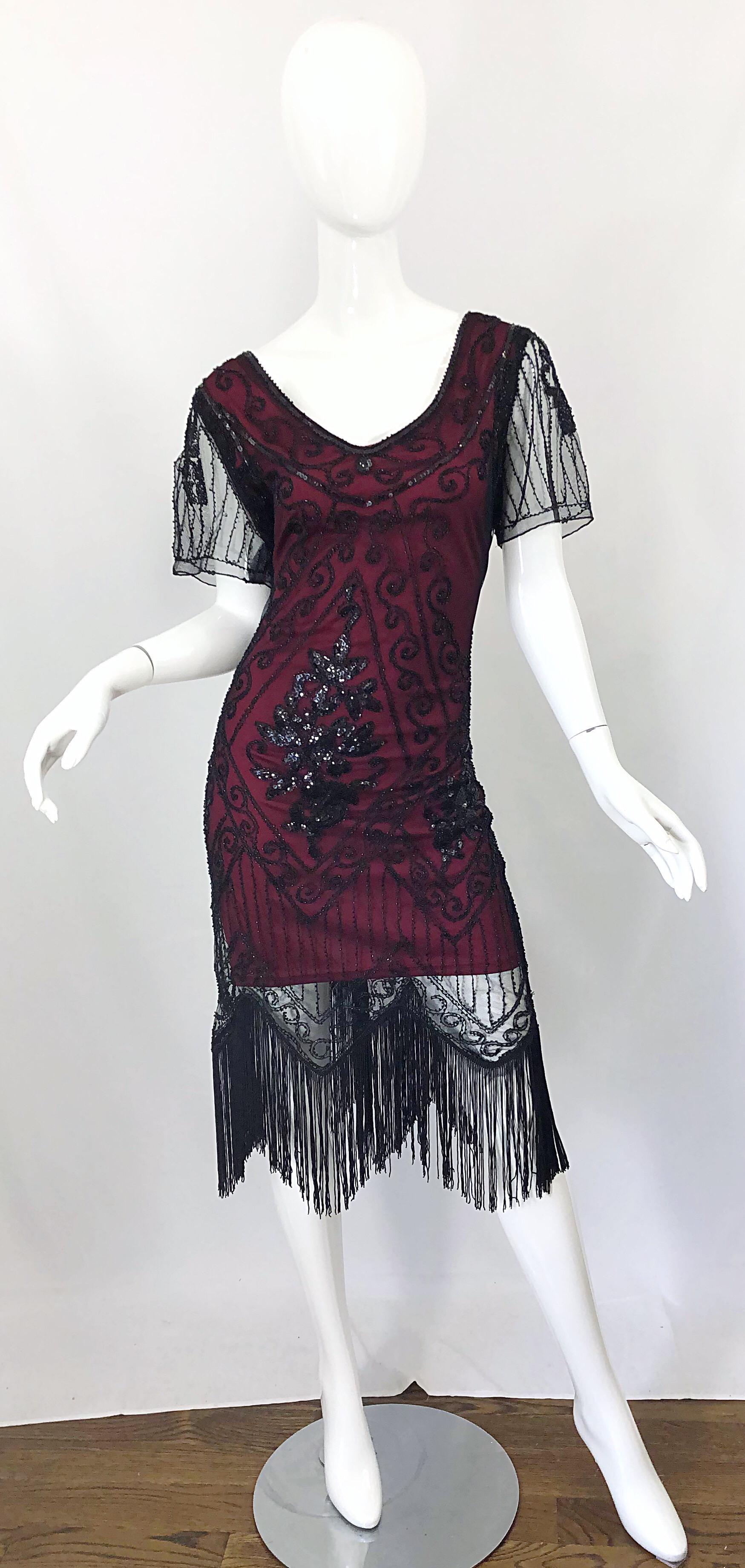 Incredible 90s does 20s black and red / maroon burgundy lace beaded fringe short sleeve flapper dress! Features a black mesh lace with thousands of hand-sewn black sequins and beads throughout. Burgundy underlay is made of jersey that stretches to