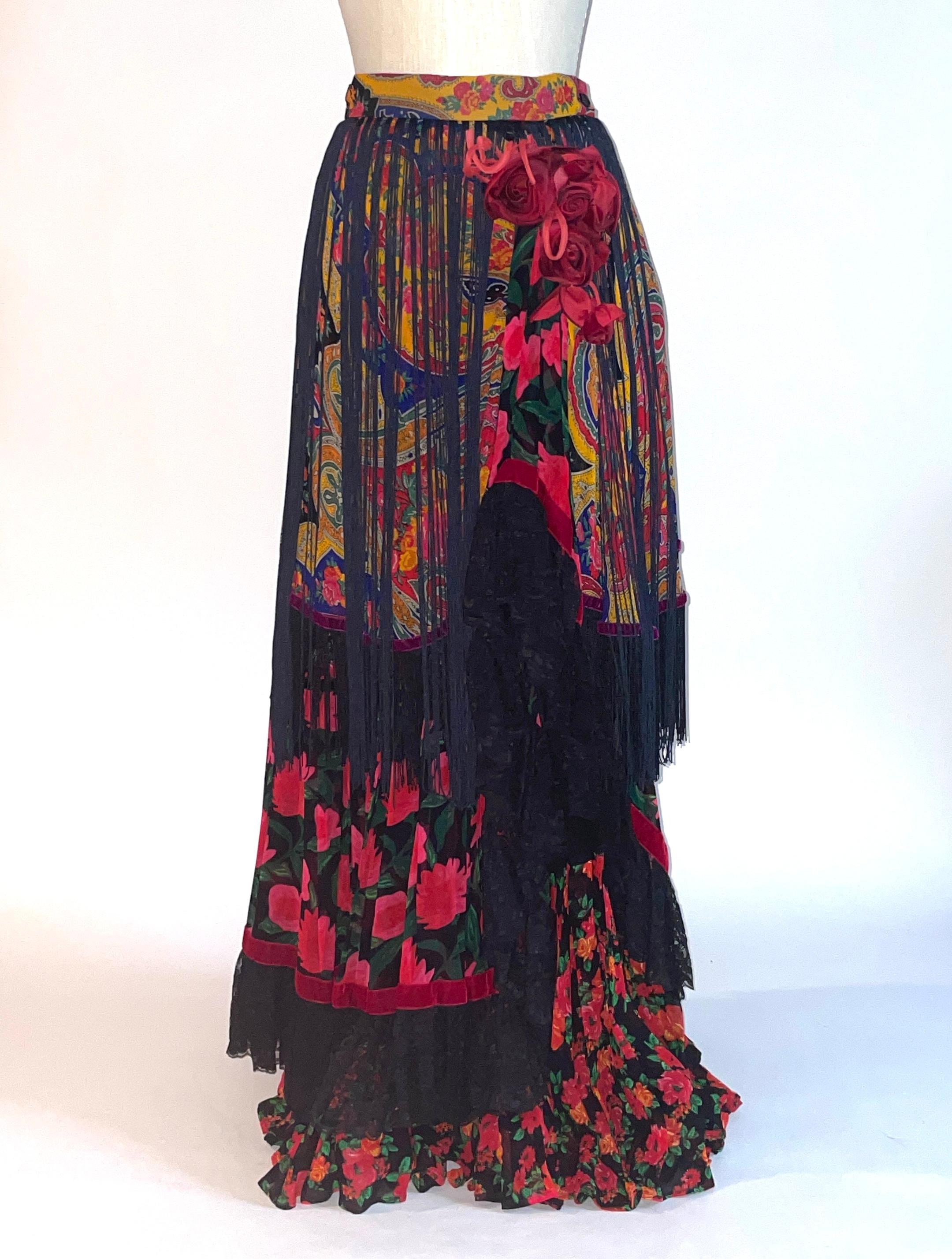 Vintage Dolce and Gabbana (circa 1990s) tiered skirt with tiered layers of floral and paisley. One tier is trimmed in lace, while another is trimmed in fringe. Additional long trim hangs from waist, and a red rose embellishment is placed at side