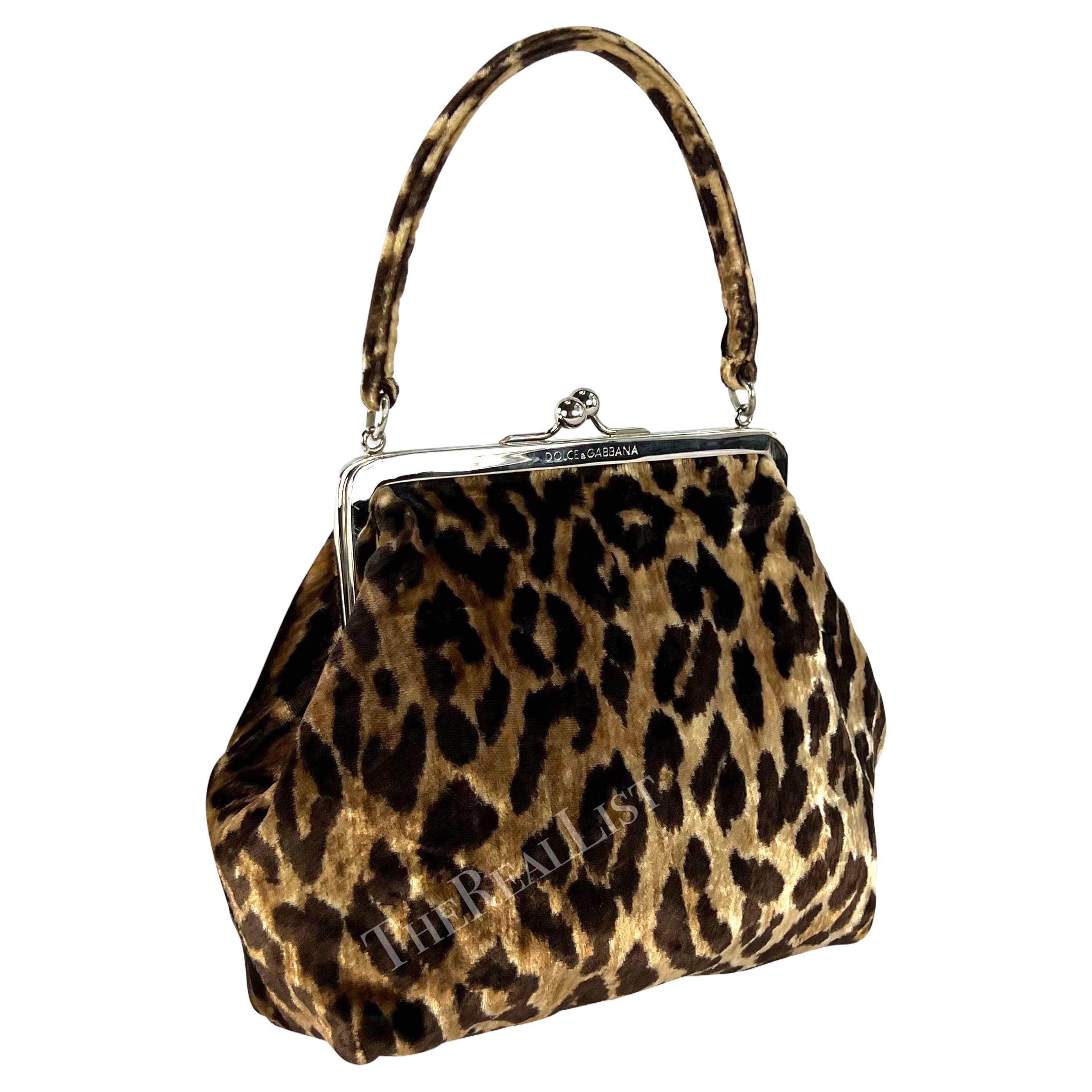 Presenting a chic velvet cheetah print Dolce & Gabbana evening bag. From the 1990s, this bag is constructed entirely of soft cheetah print velvet. The bag features a top handle and is made complete with a silver-tone clam shell closure.
