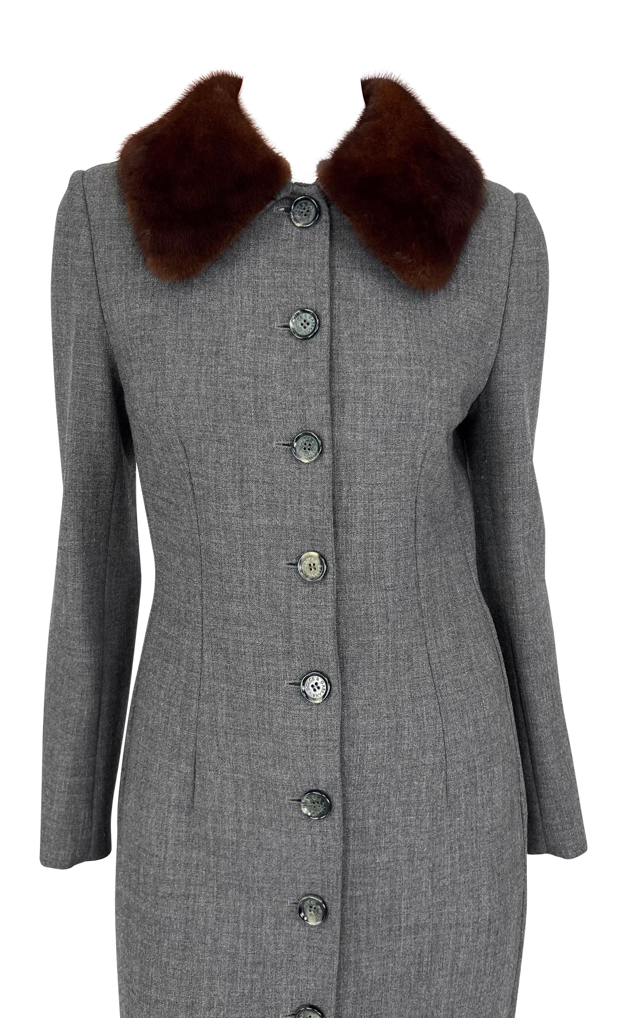 Questo cappotto grigio di Dolce & Gabbana degli anni '90 è caratterizzato da un design sartoriale con un frontale abbottonato e un collo in vera pelliccia di visone. 

Misure approssimative:
Taglia - IT38 
Busto: 34
