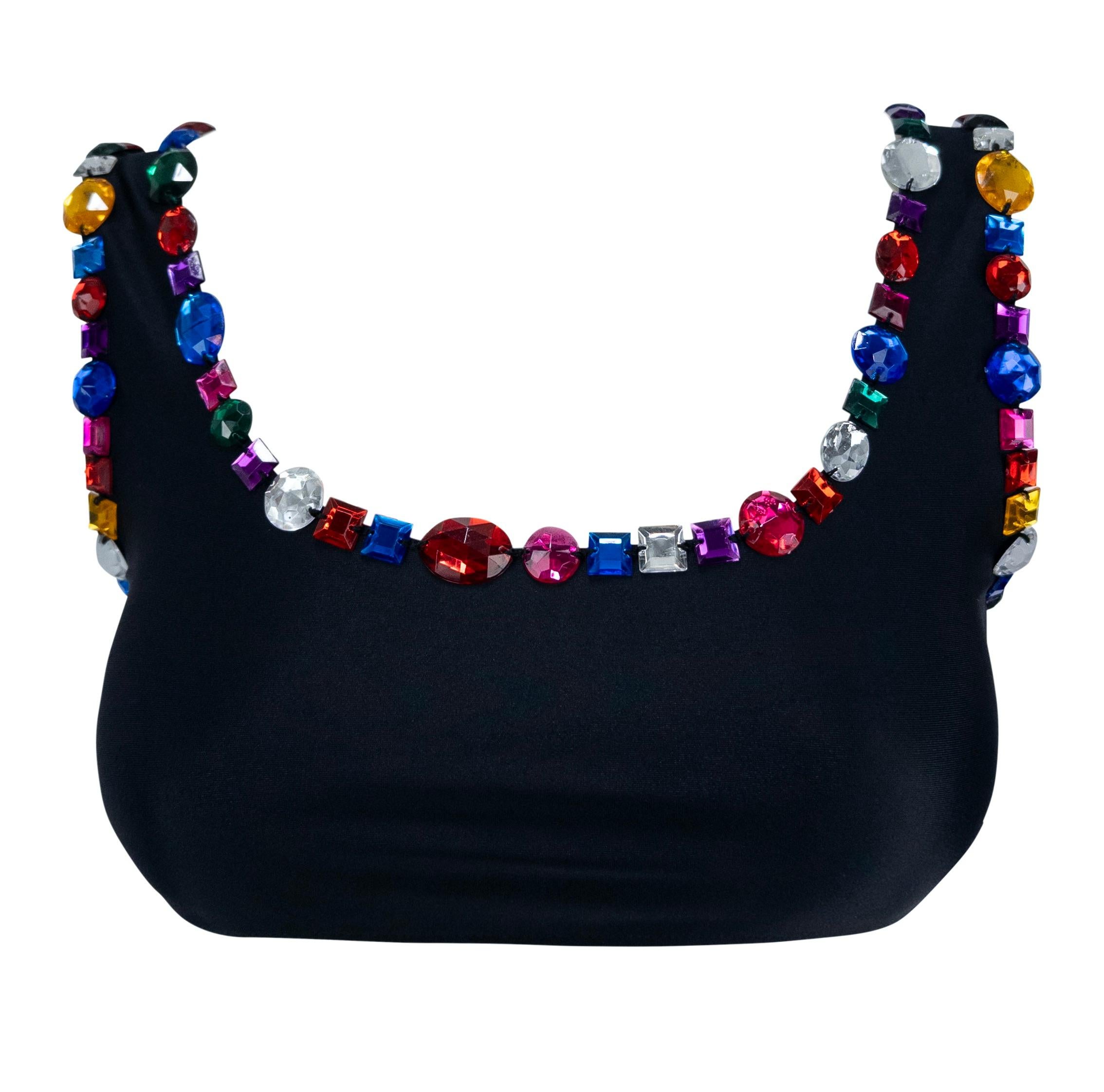 This playful Dolce & Gabbana swim skirt set from the 1990s features a sleek black bikini-style crop top and matching mini skirt, each trimmed with oversized multicolor rhinestones. The bold jeweled embellishments add a vibrant, glamorous touch to