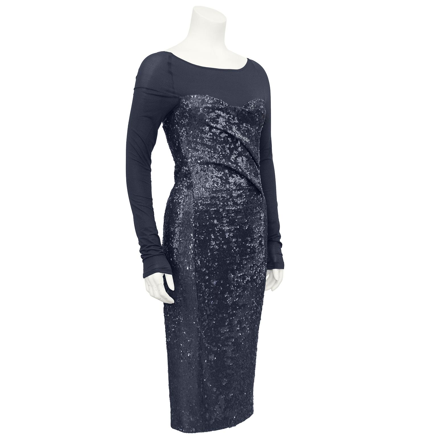 Very chic Donna Karan cocktail dress from the 1990s. Sheer charcoal grey sleeves and yoke that give the illusion of a sheer body suit under a strapless sequin dress. The charcoal grey sequin body has a twisted sweetheart neckline, is fitted through