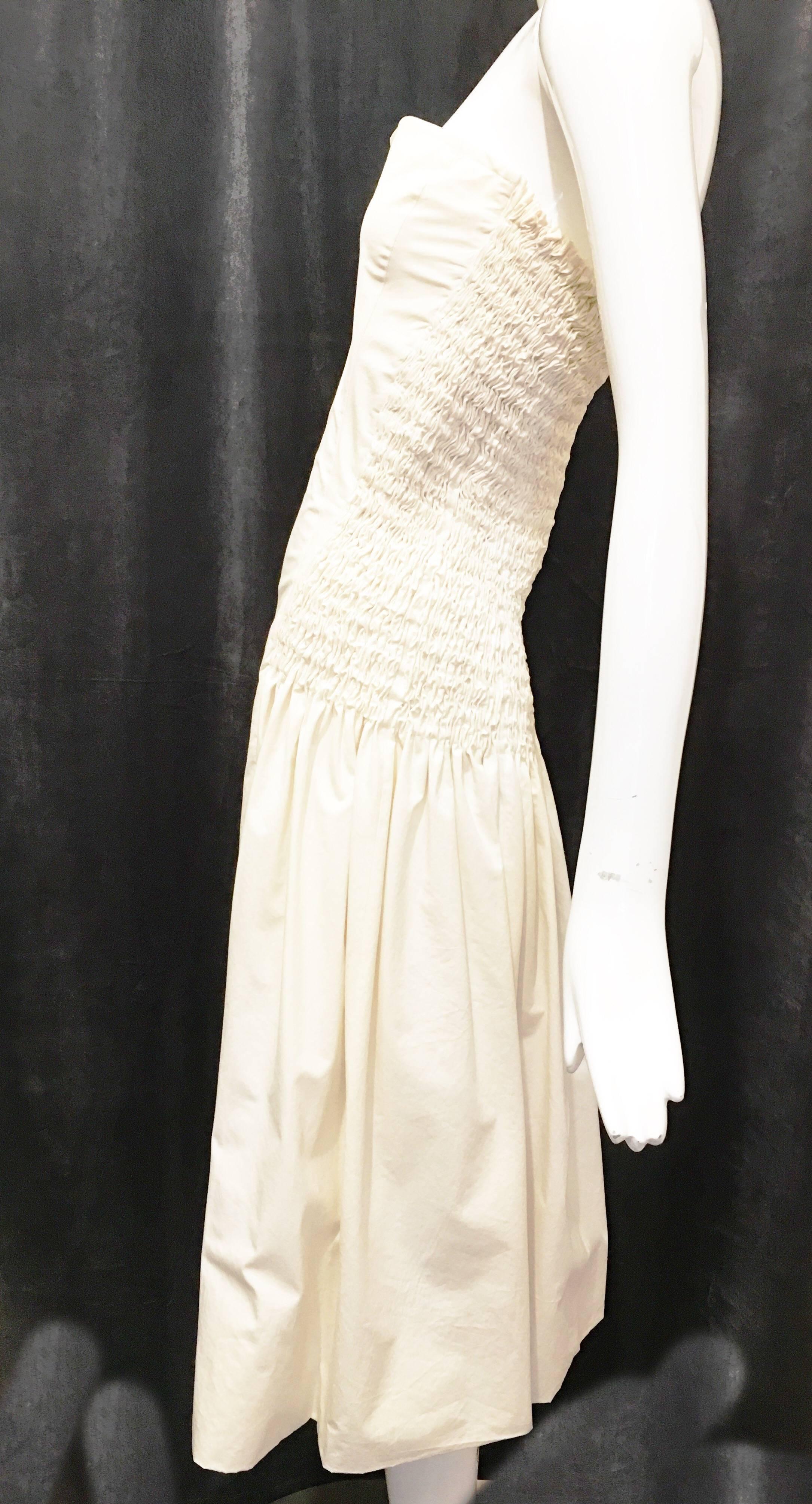 Strapless cream colored knee length casual summer dress. Gathered at the back/sides with elastic. Rolled hem. Could be dressed up with a pair of heeled sandals for a summer wedding guest look. A comfortable dress to lounge around in in warm weather.