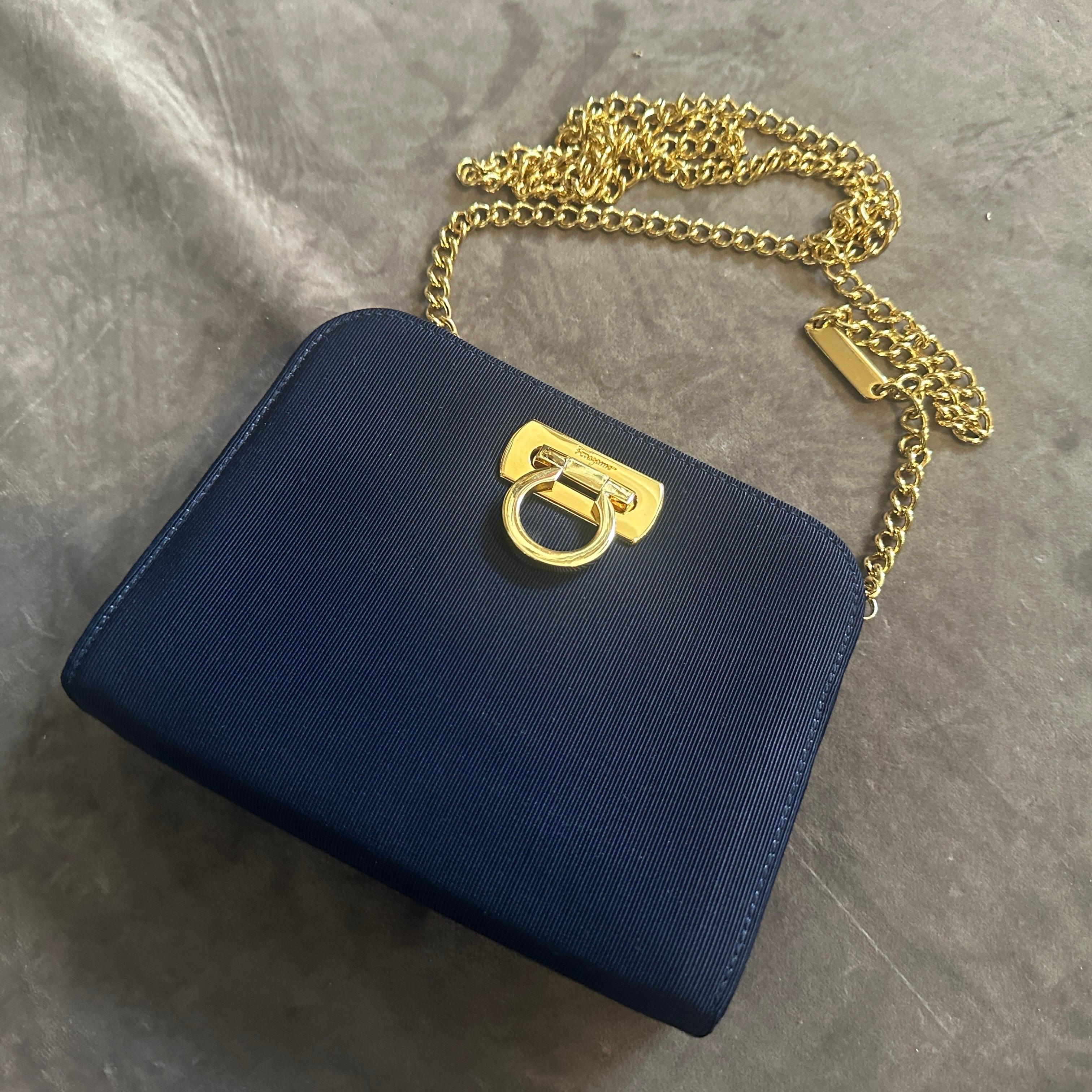 This sophisticated 1990s Salvatore Ferragamo belt bag is a perfect example of the brand's enduring commitment to elegant design and Italian craftsmanship. The bag's structured silhouette is covered in a deep navy or sapphire blue fabric, likely a