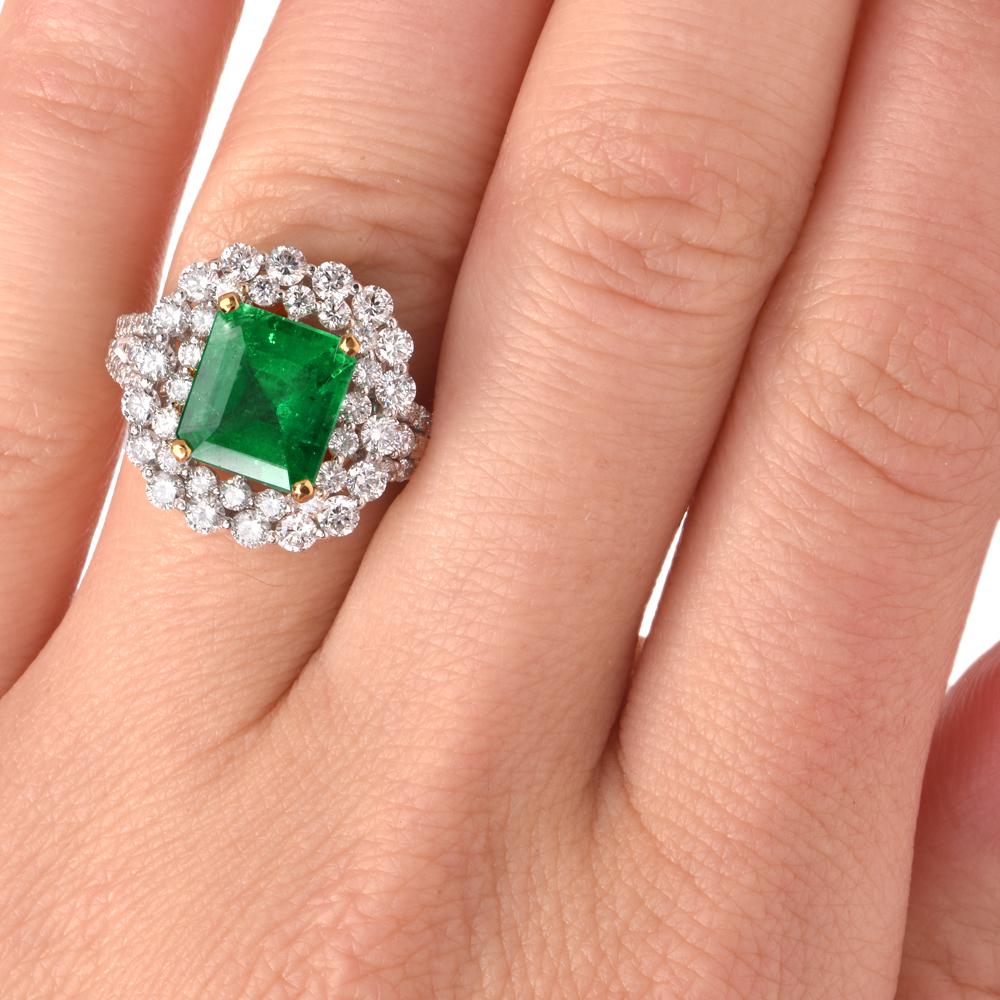 This stunning estate emerald and diamond cocktail ring is crafted in 18k white gold. Showcasing a centered genuine emerald-cut emerald approx. 2.54 carats surrounded by a double halo of 62 round-cut diamonds  and 2 baguettecut diamond, all  approx.