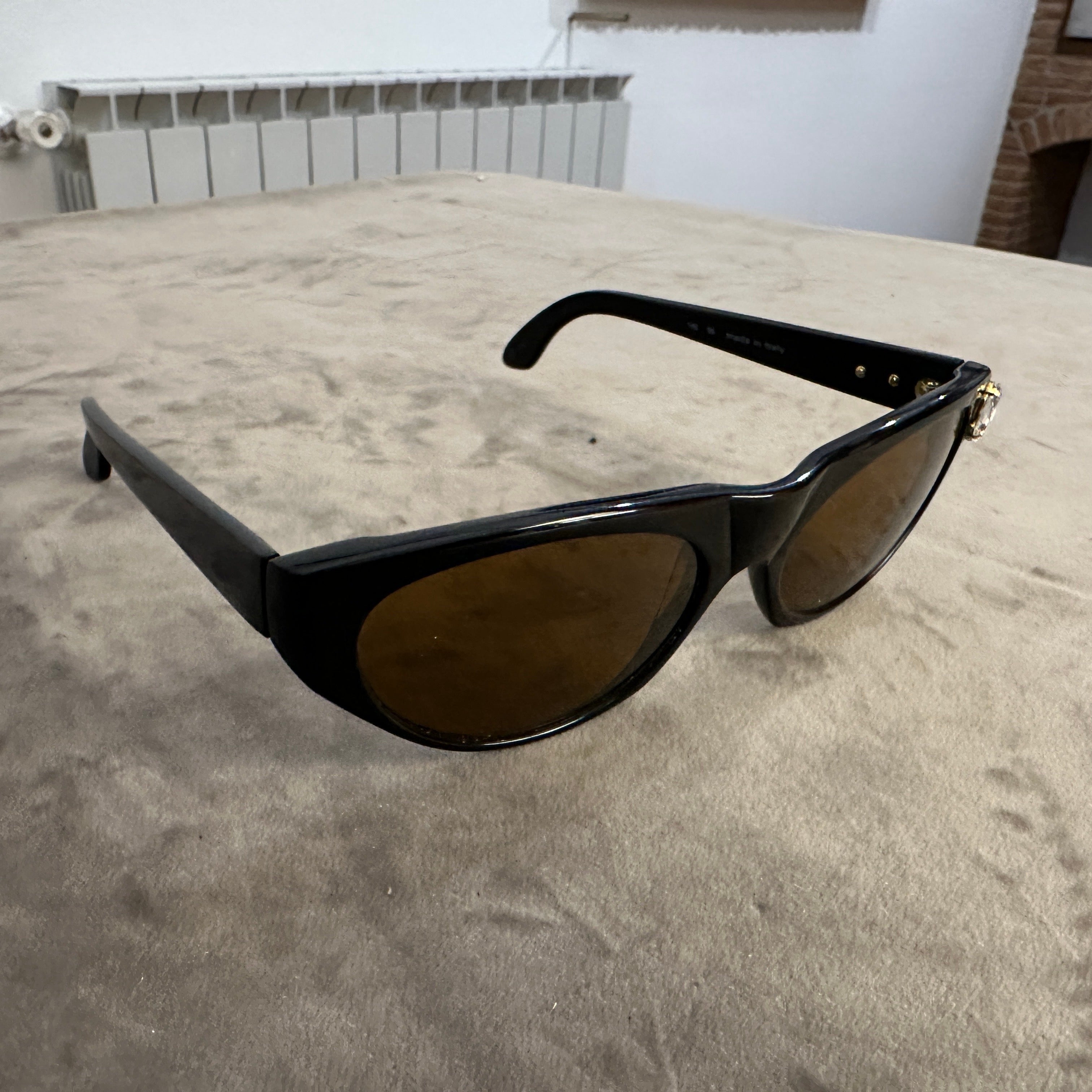 Ces lunettes de soleil Emmanuel Ungaro des années 1990 incarnent l'esthétique audacieuse et glamour de la mode vintage. Les montures présentent un design œil de chat saisissant, réalisé en acétate noir brillant, qui exsude une sophistication