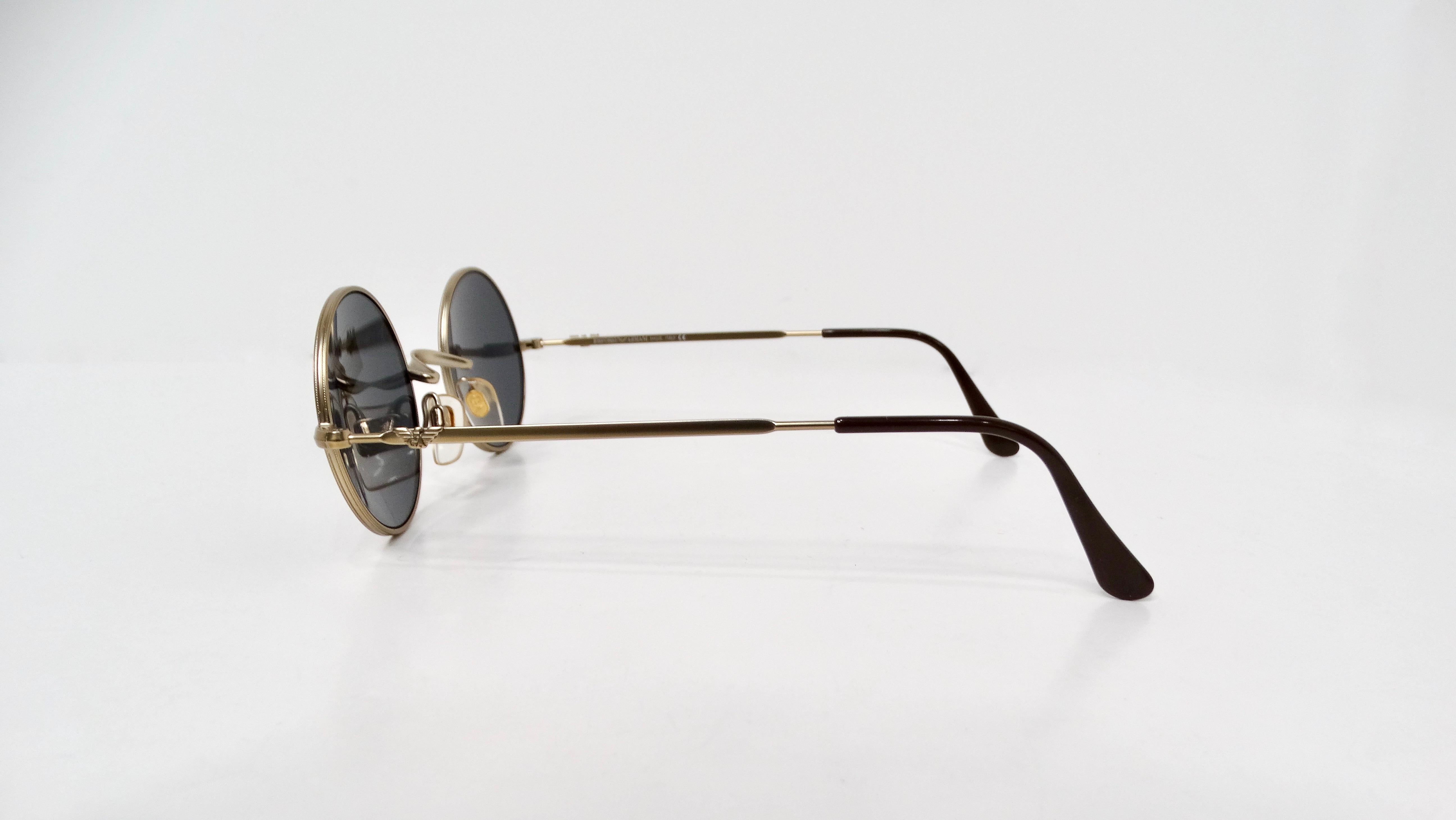These iconic 1990s Emporio Armani black round frame sunglasses embody the essence of vintage sophistication and timeless elegance. Crafted with a sleek black frame and striking gold-tone metal accents, they exude a refined aesthetic that captures