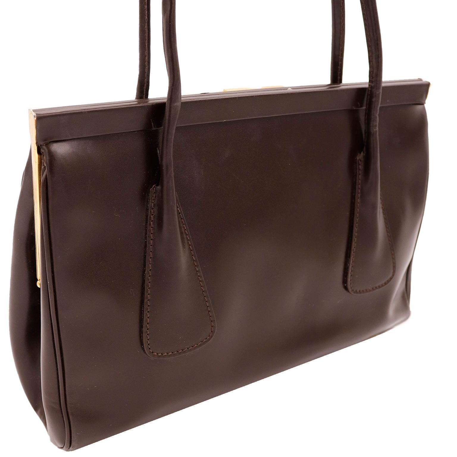 This luxe Escada dark chocolate brown leather handbag has double top handles and features a gold Escada name plate on the front. We love these kinds of bags because they elevate your daywear with instant sophistication! This classic bag has a hinged