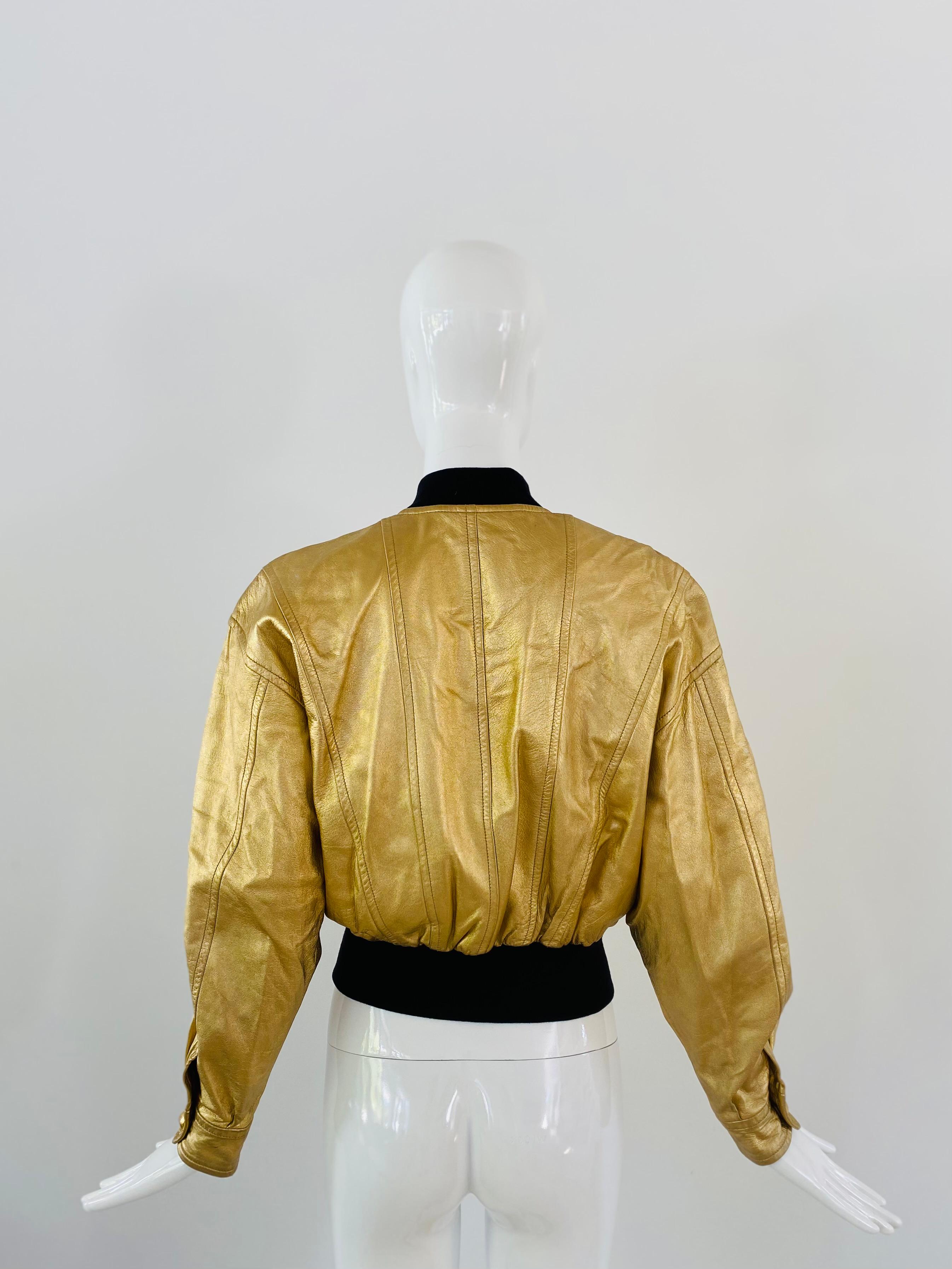 1990s Escada leather bomber jacket in gold leather with embroidered stars, gold snap buttons, and a stretchable waistband. Some fading to the gold on the leather and a hole was made in the inside lining of the jacket which has been patched up.