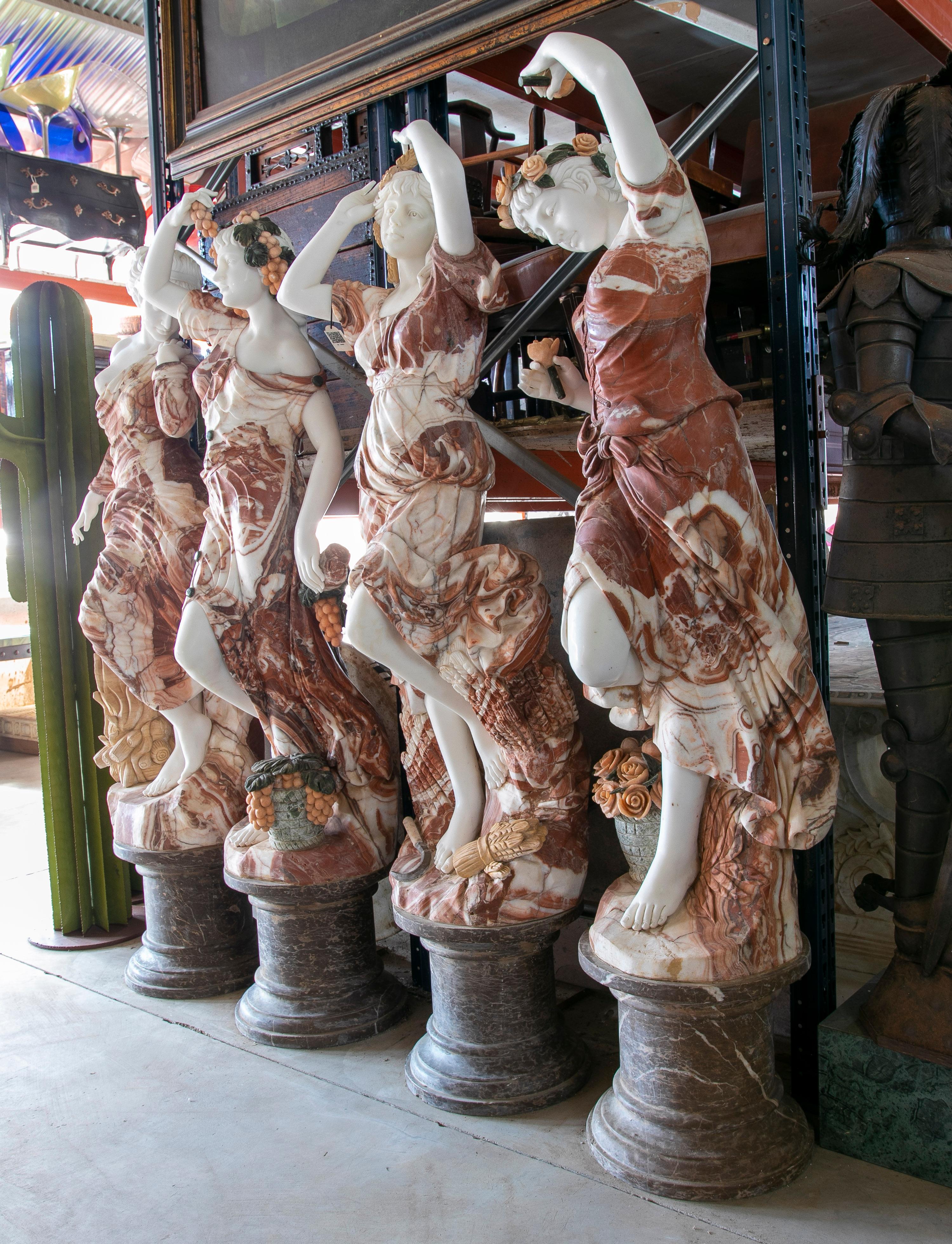 Classical 1990s European hand carved set of four seasons dancing with bases. Four woman statues carved out of mainly Alicante red, Carrara white and Emperador brown marble, with Serpentine green, Rosetta pink and Giallo yellow for the various