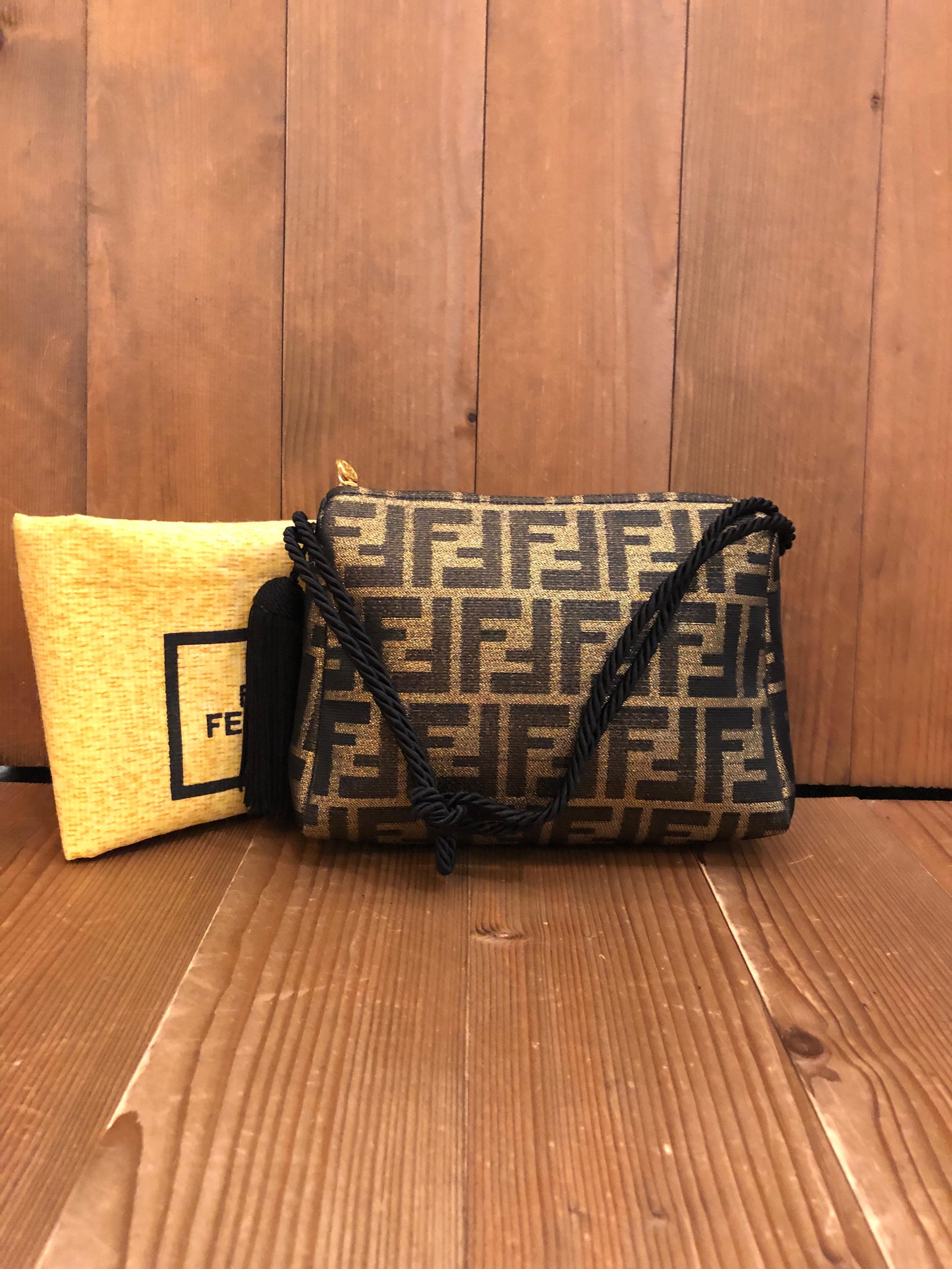 This very rare FENDI pouch handbag is crafted of Fendi's iconic Zucca jacquard in gold and black. Top zipper closure opens to a black jacquard interior featuring a patch pocket. The handle of this pouch is made out of black silk ropes tied together
