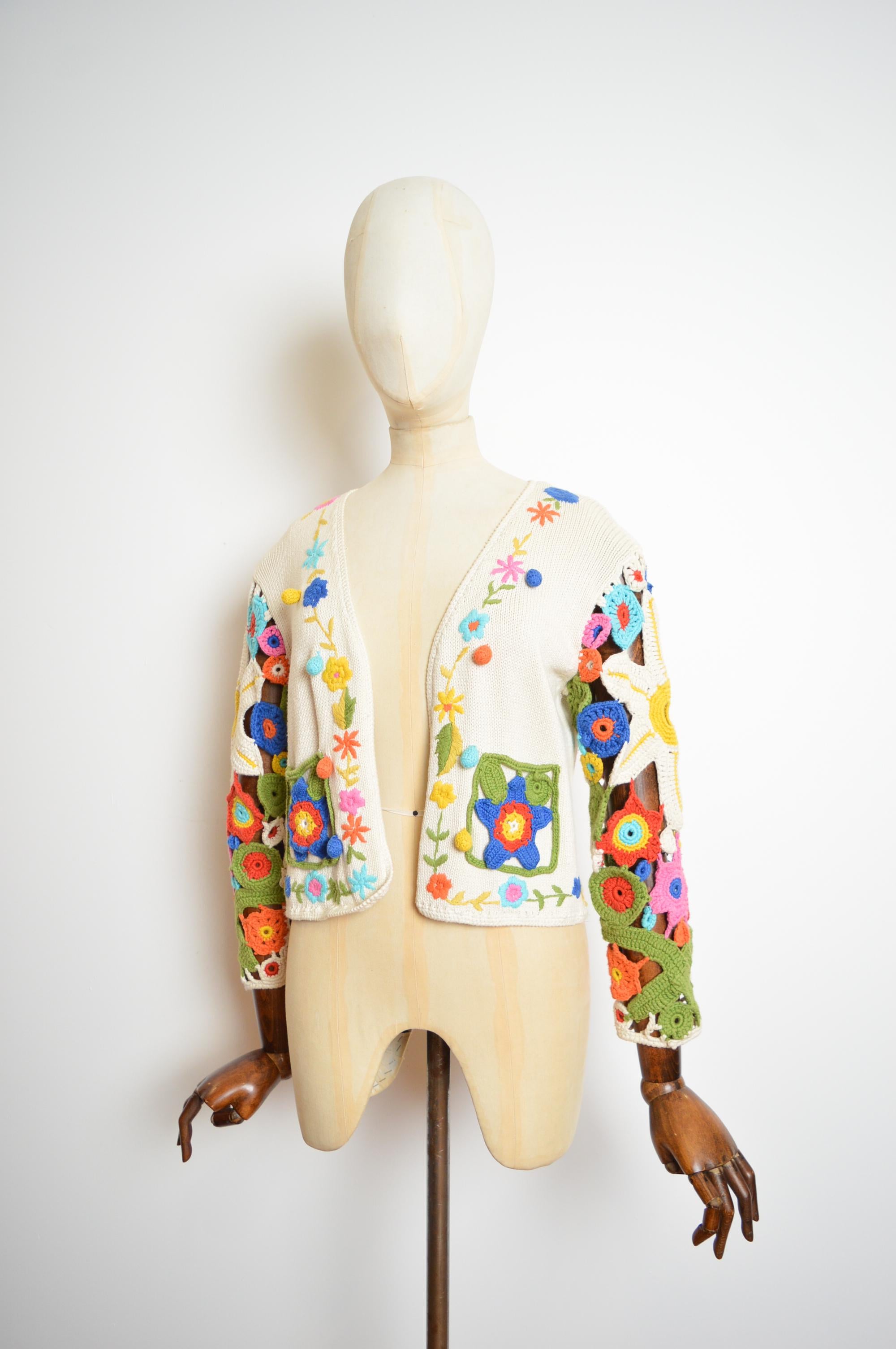 A Chic and fun early nineties Franco Moschino colourful crochet knit - open front cardigan from the iconic 'Cheap & Chic' line ! 

MADE IN ITALY.  

Features; Cream crochet knit with vibrant floral colourful appliqué, Hip pockets, long sleeves,