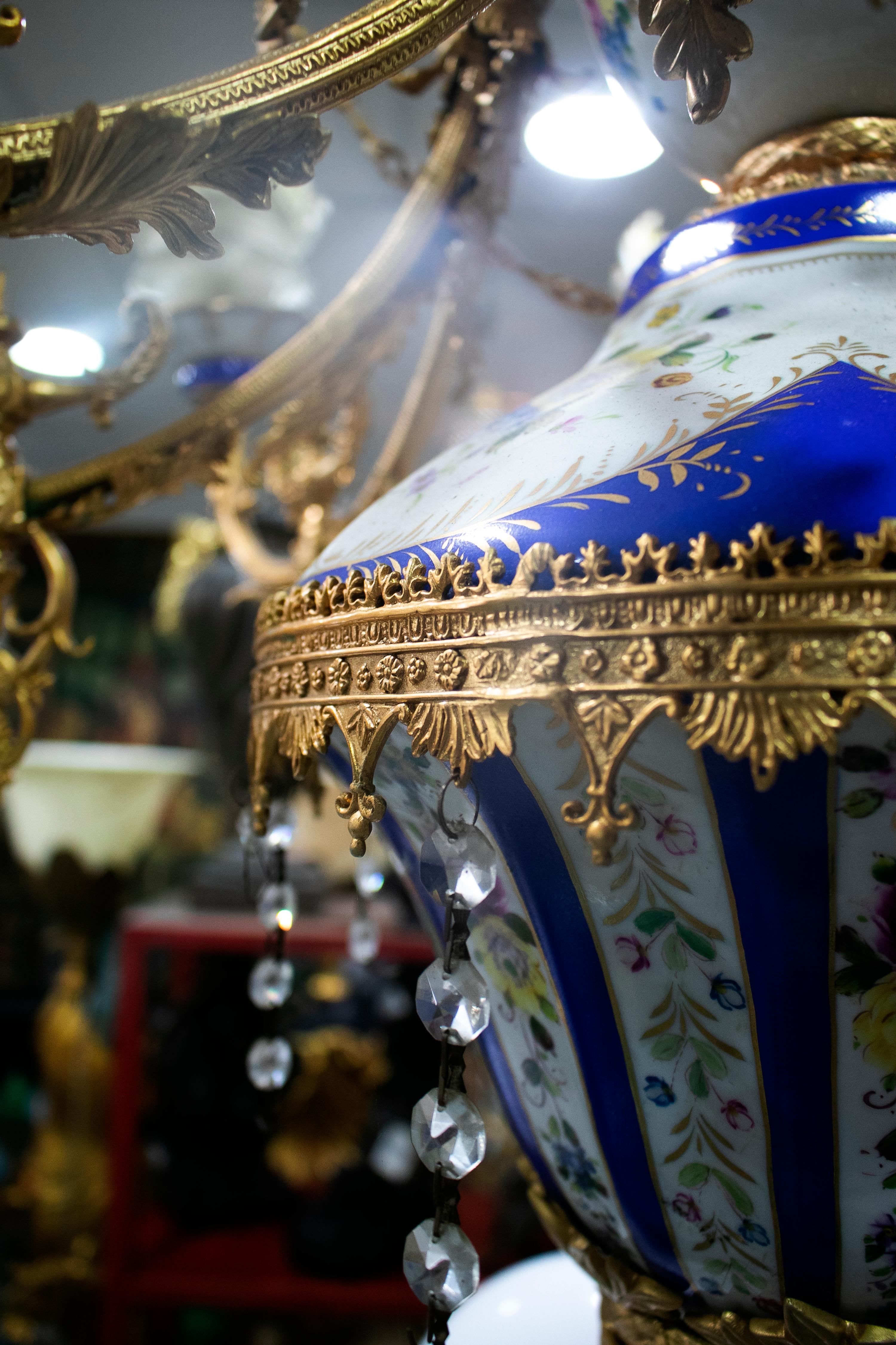 Ornate 1990s French white and cobalt blue hand painted porcelain chandelier with 10 golden bronze arms and hanging glass ornaments.