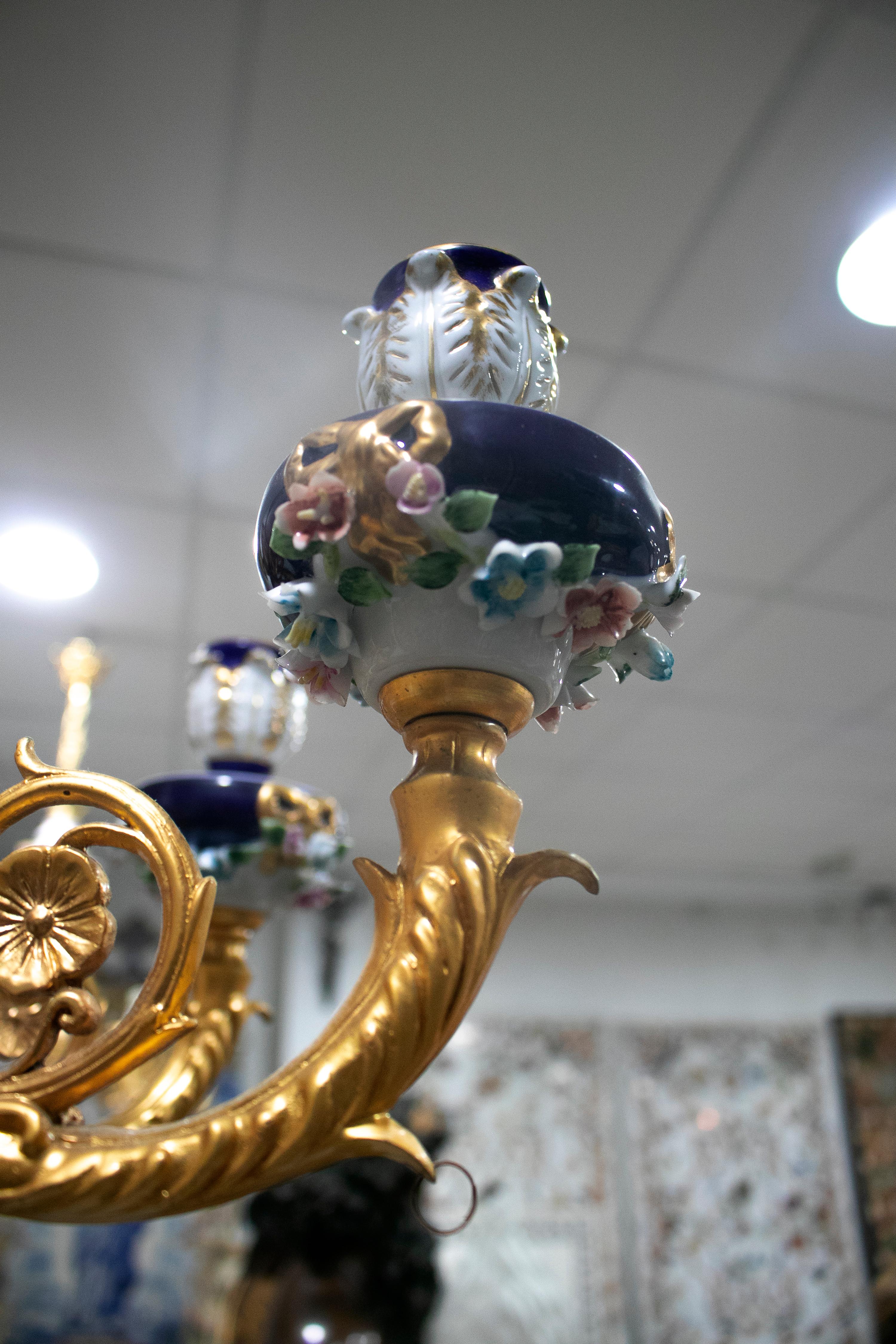 Ornate 1990s French white and cobalt blue hand painted porcelain chandelier with 8 golden bronze arms and hanging glass ornaments.
  